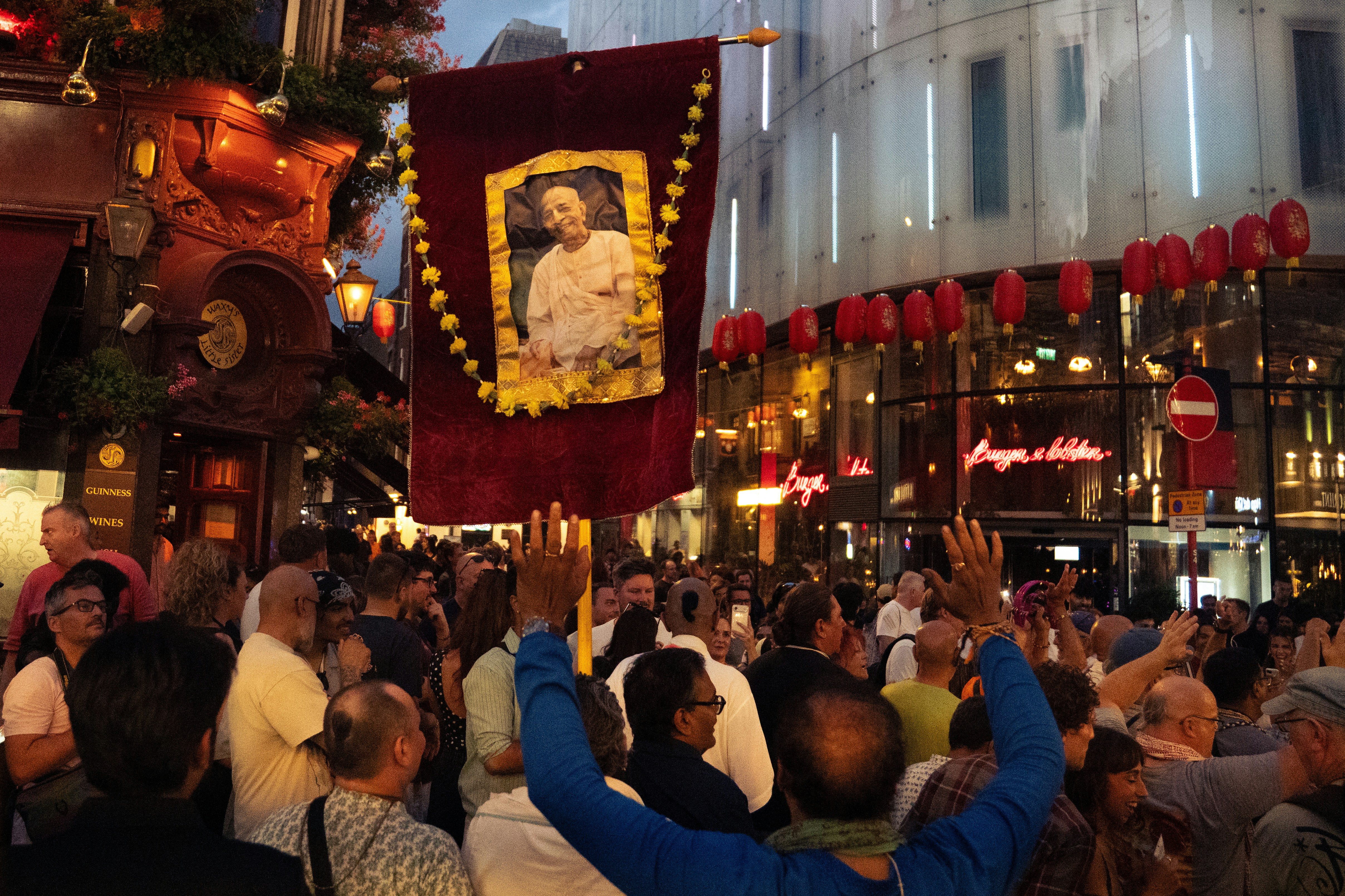 A crowd of people on a city street with a large red banner