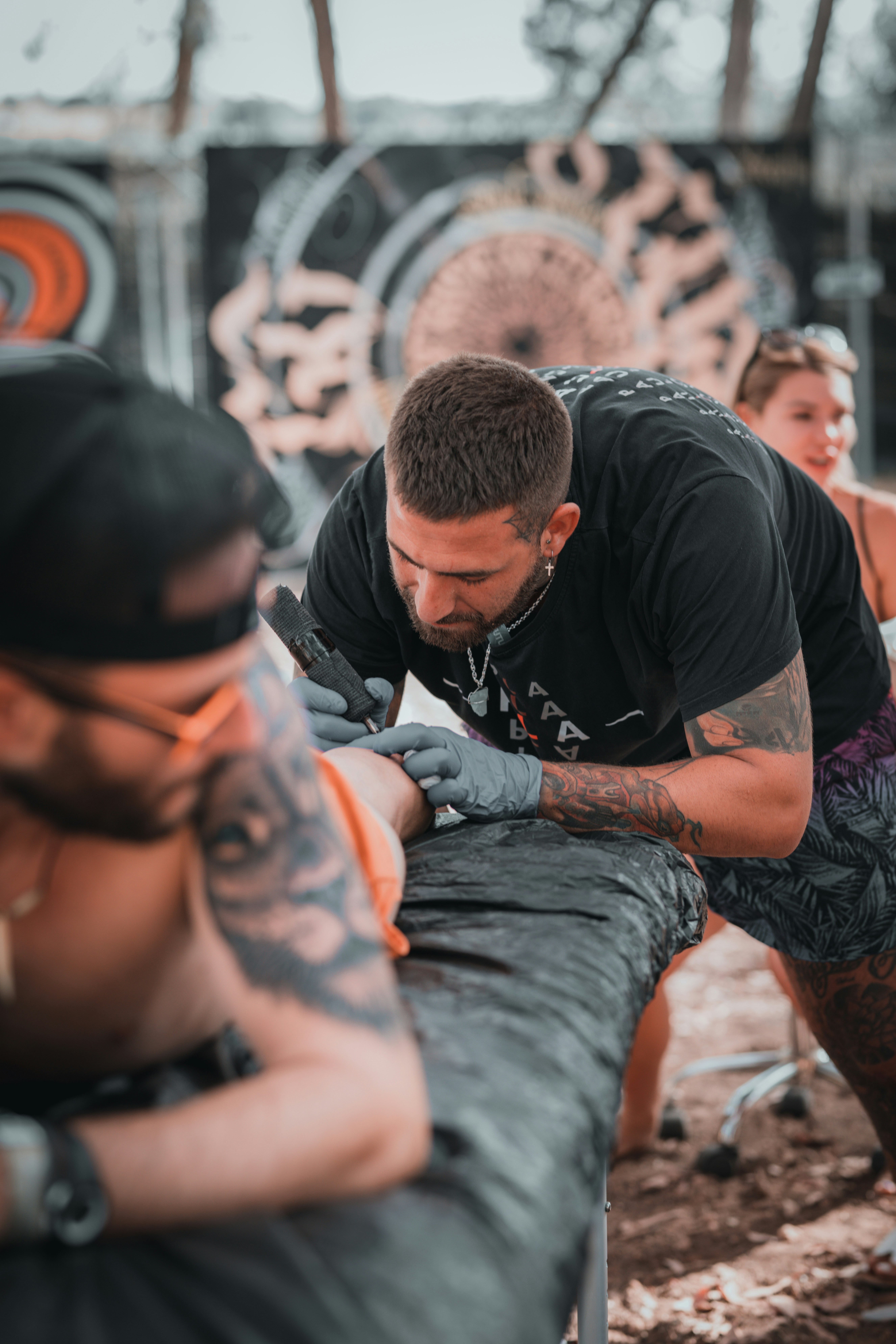 Un tatuador con camiseta negra tatuando a una persona sobre una mesa