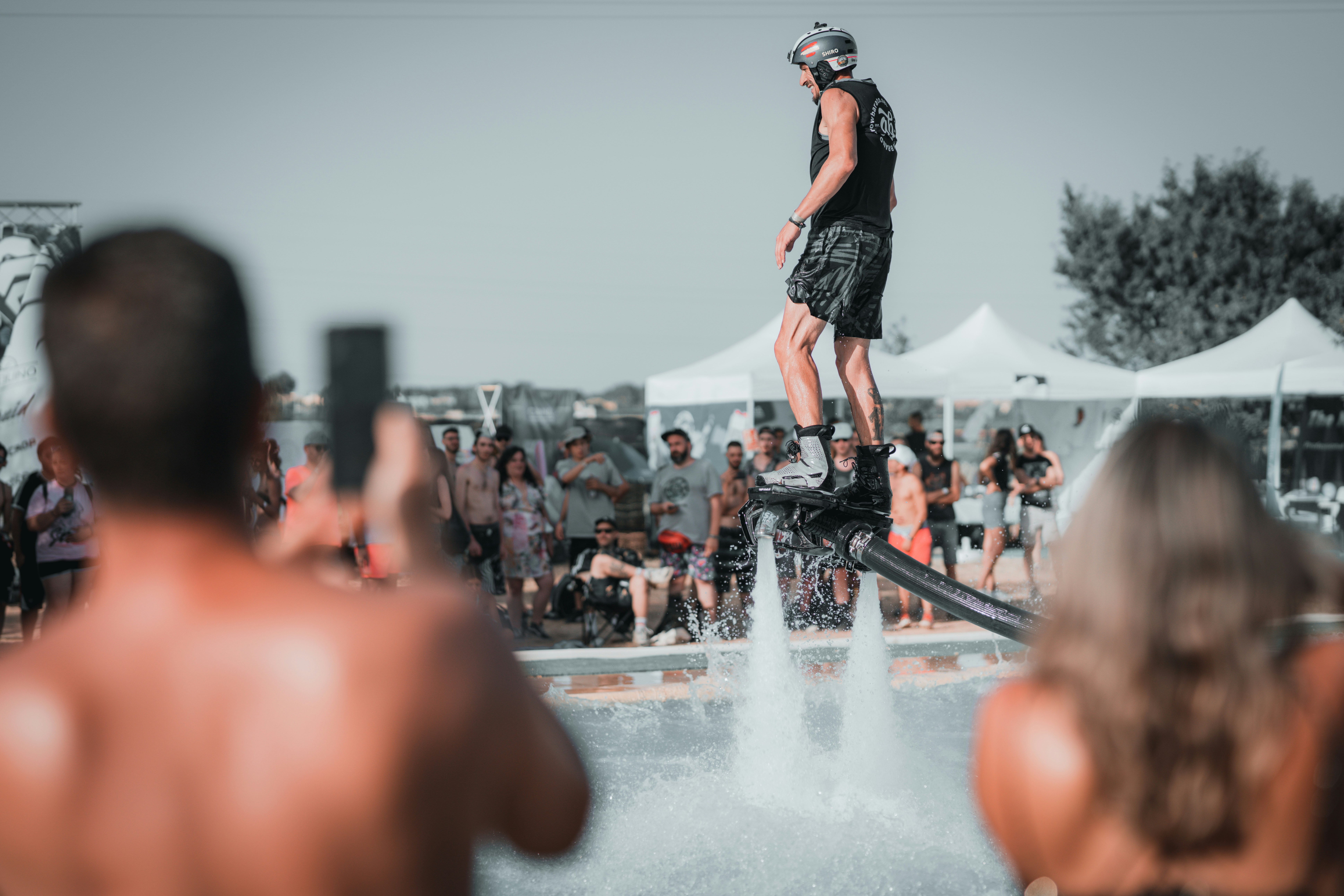Una persona en un flyboard flotando sobre el agua ante una multitud de espectadores