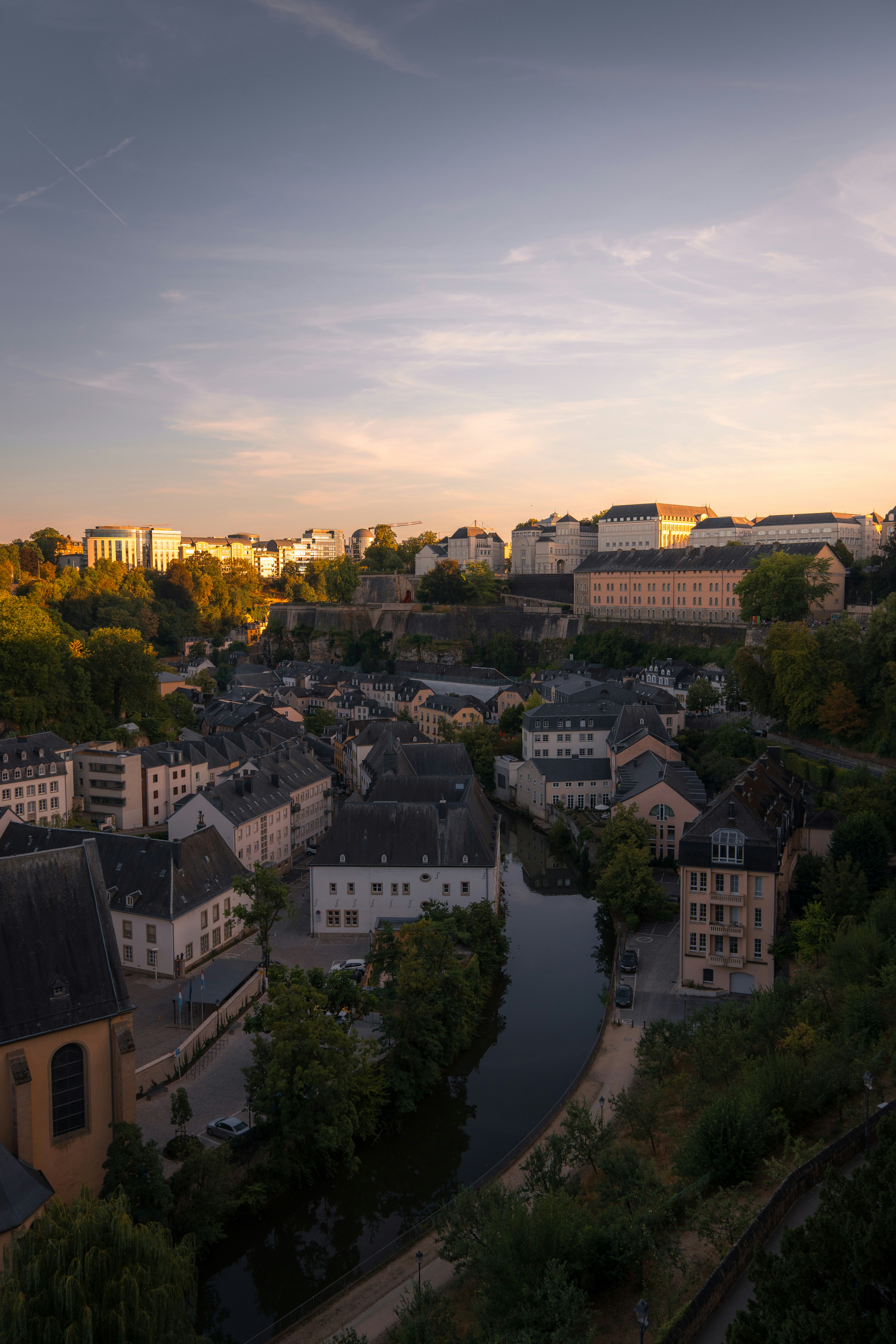 A river flowing through the historic Grund district in Luxembourg City at golden hour