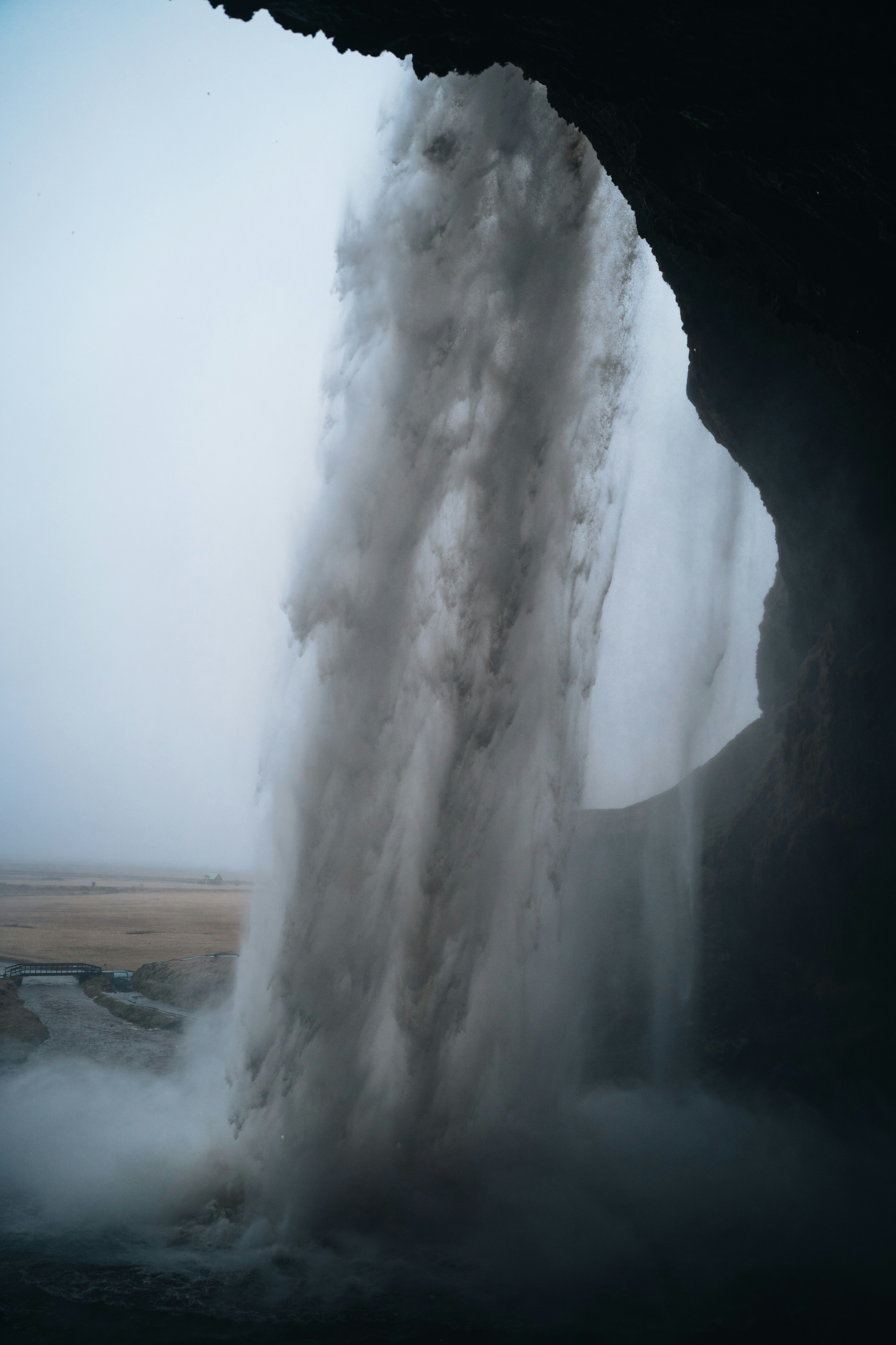 A powerful waterfall cascading over a dark cliff into a misty landscape