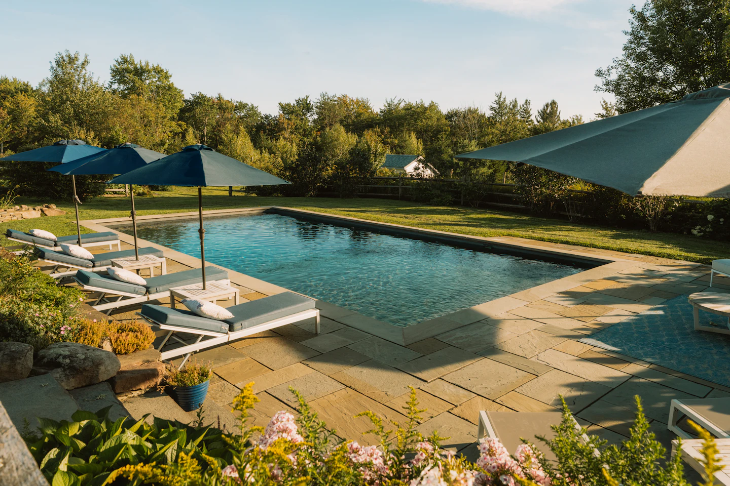 Stone pool terrace with lounge chairs and blue umbrellas