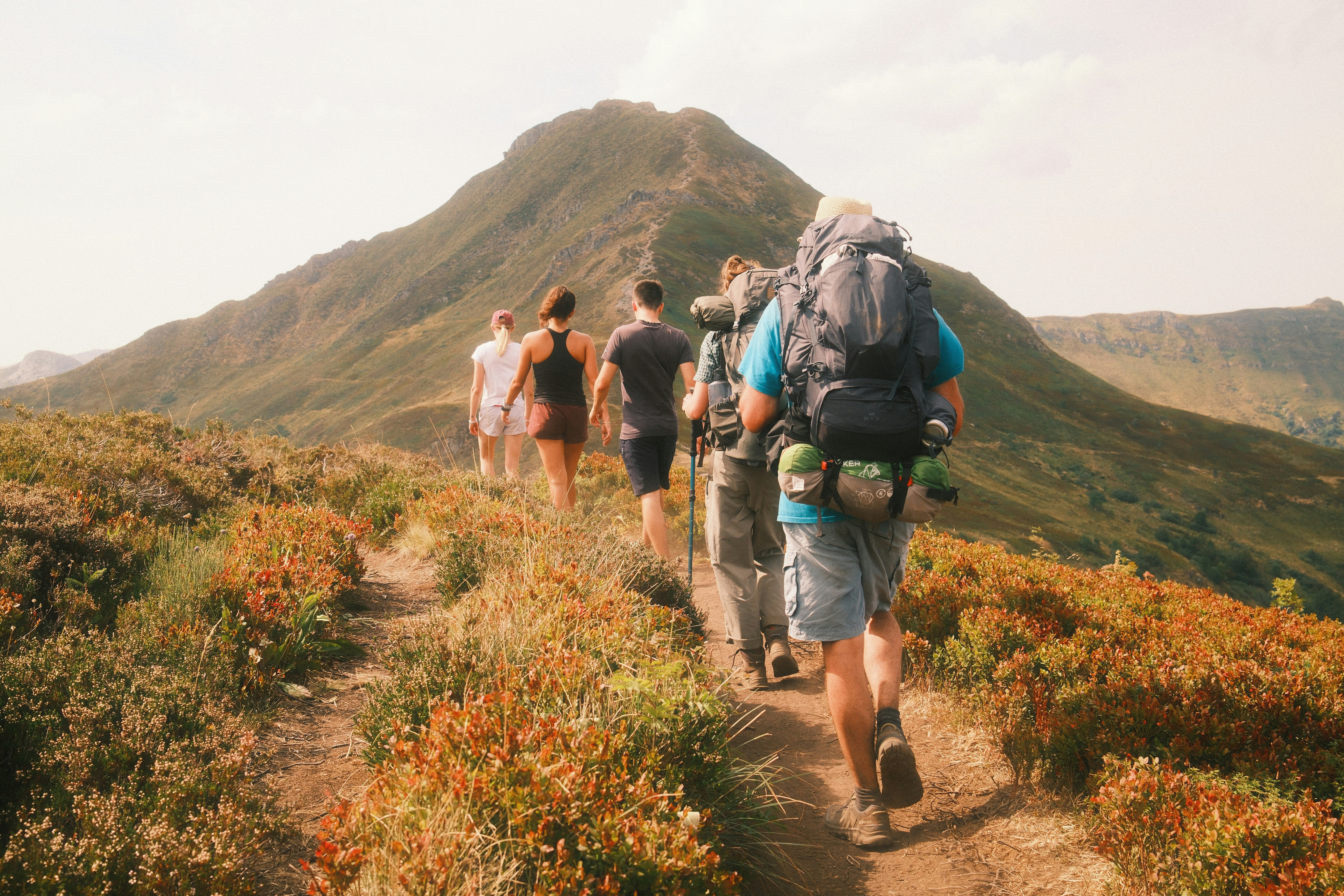 A group of people hiking on a trail toward a large mountain peak