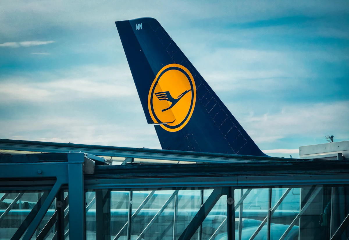 The blue tail fin of a Lufthansa airplane against a cloudy sky