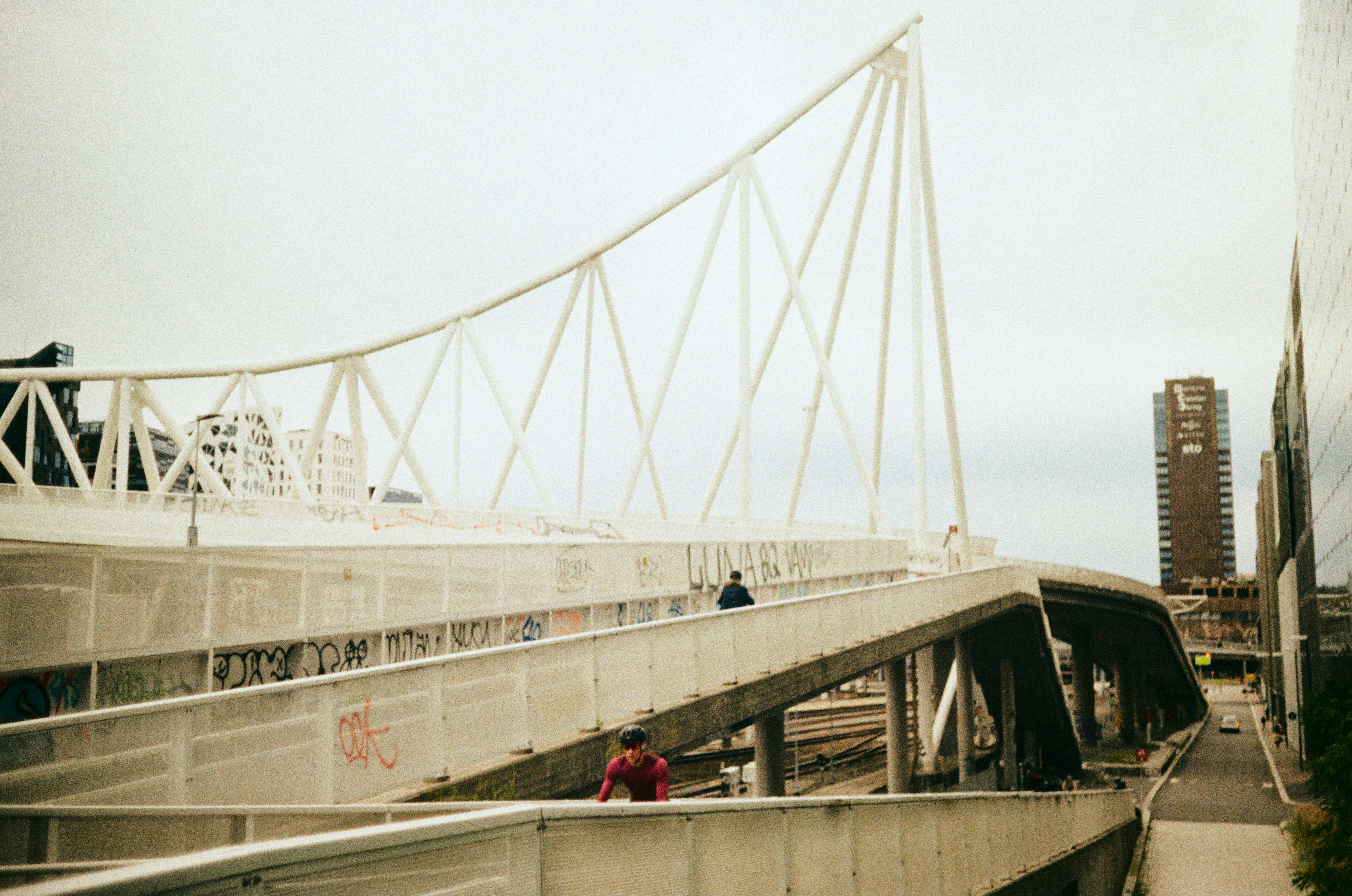 Cyclist riding over a white pedestrian bridge