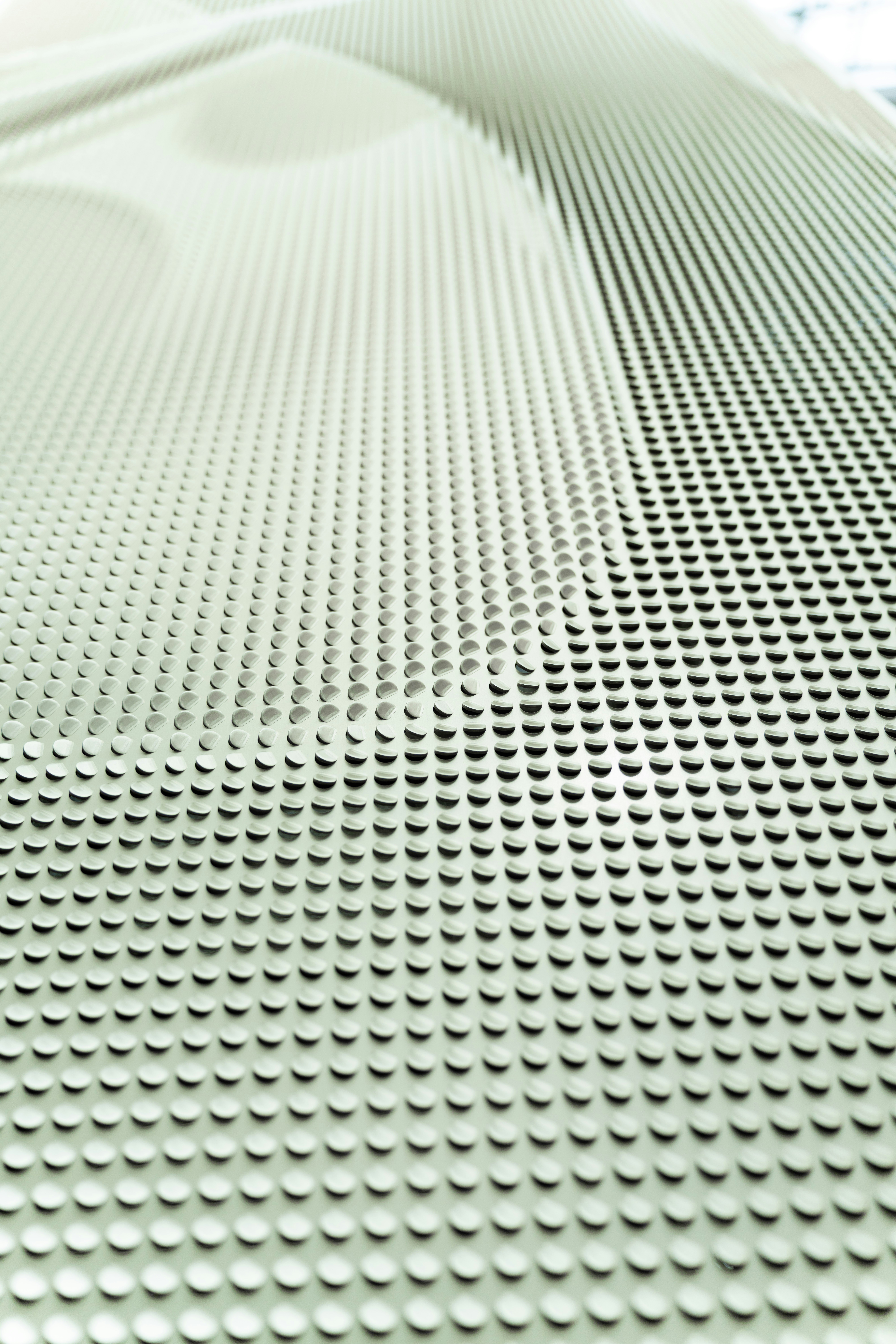 A white surface with a repeating pattern of small raised circular bumps