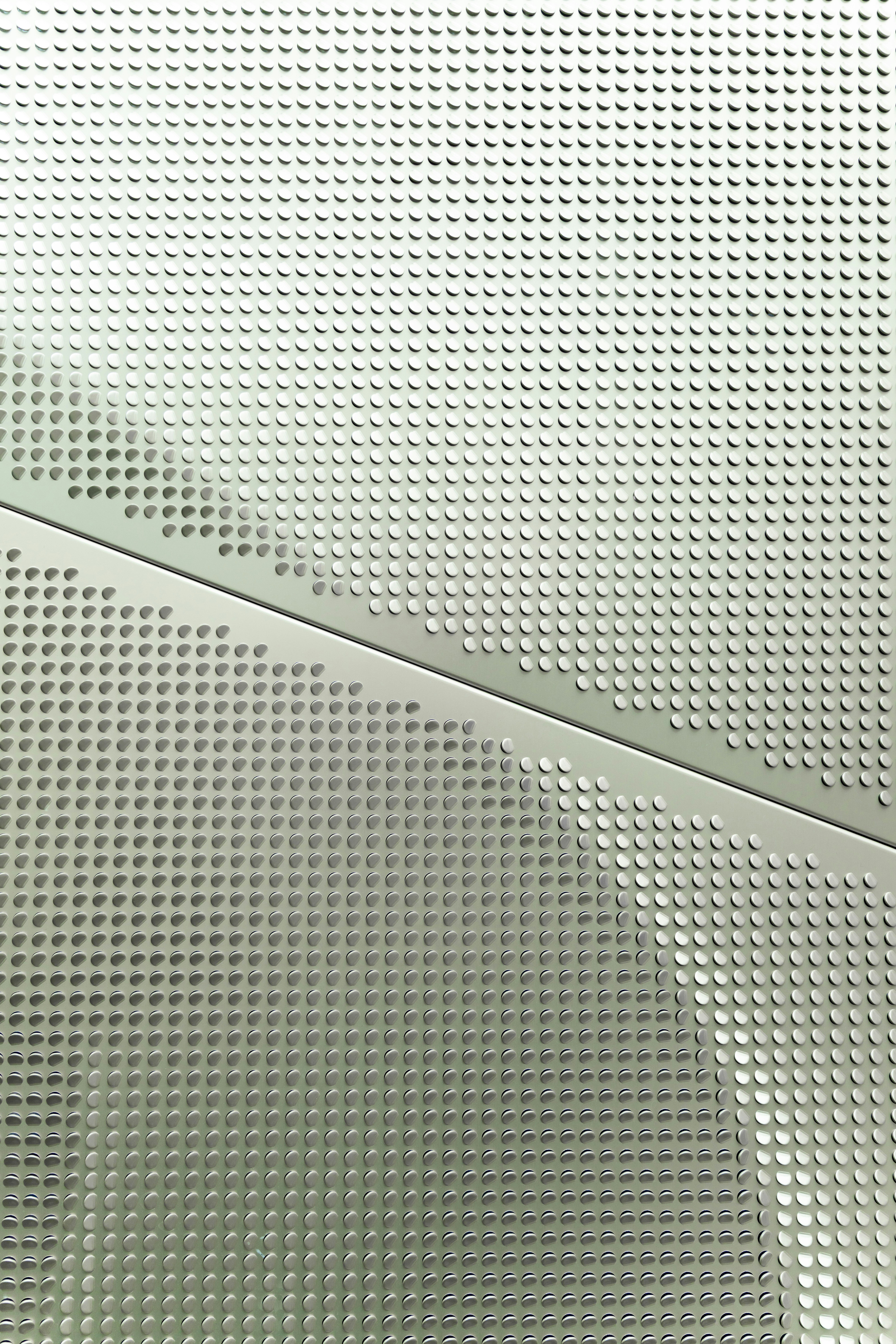 A light grey metal panel with a repeating pattern of small circular indentations