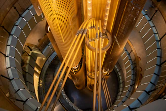A high-angle view of a spiral staircase surrounding a central yellow industrial column