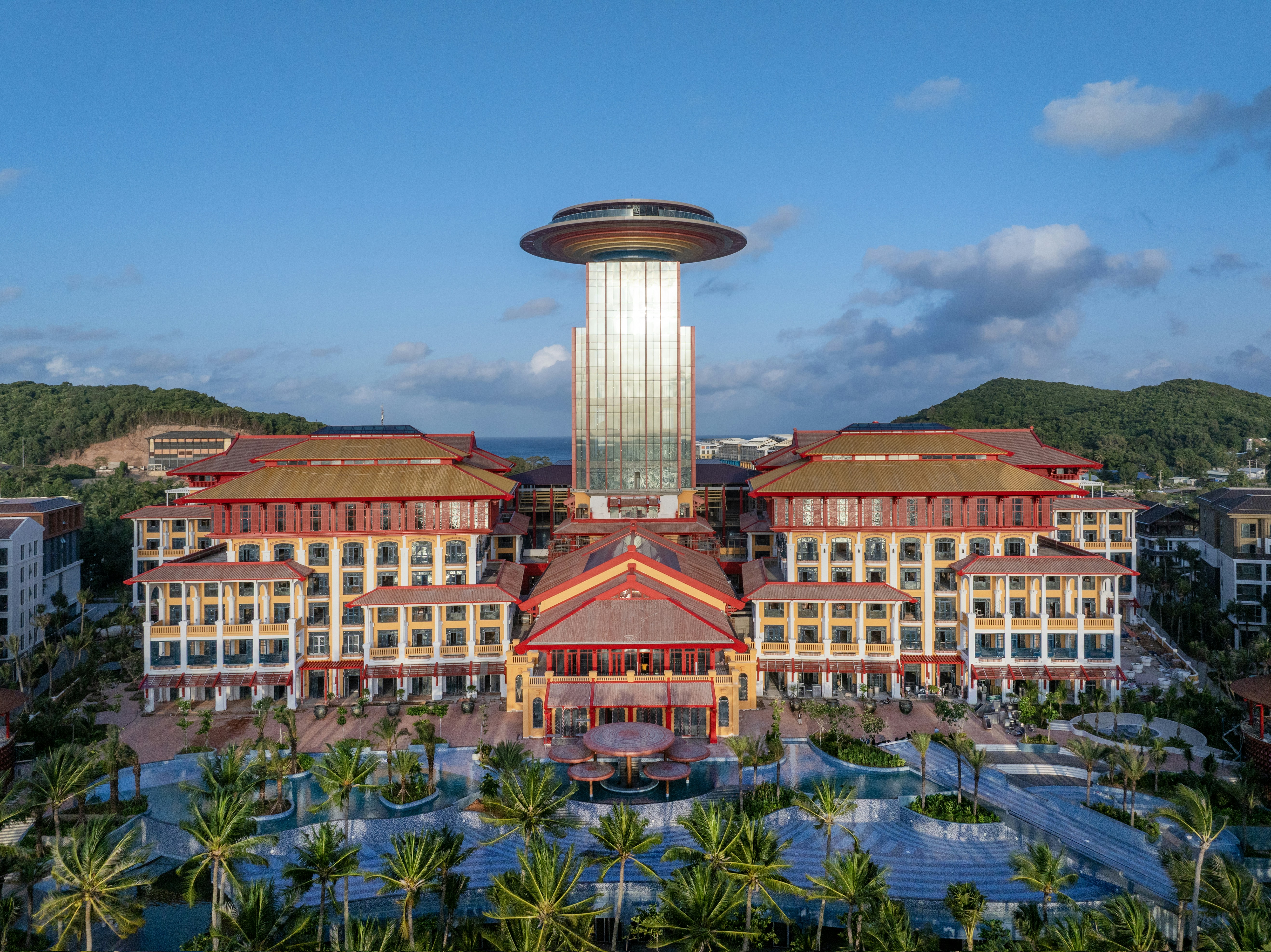 Aerial view of a large resort with a central tower and palm trees