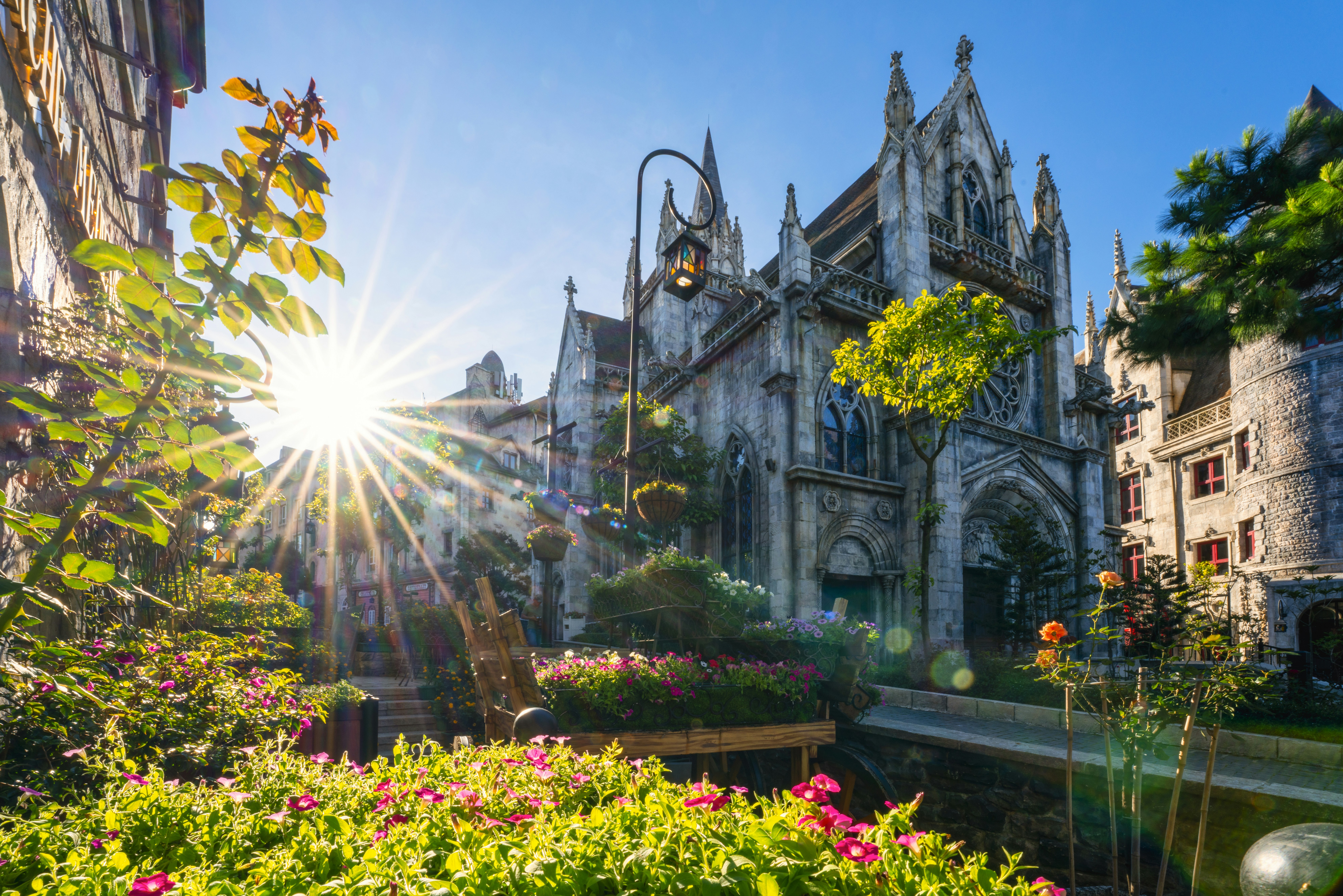 Gothic stone church with a sunburst in a garden of pink flowers