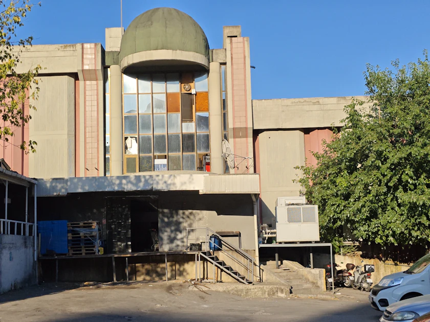 A concrete warehouse building with a loading dock and a domed entrance.