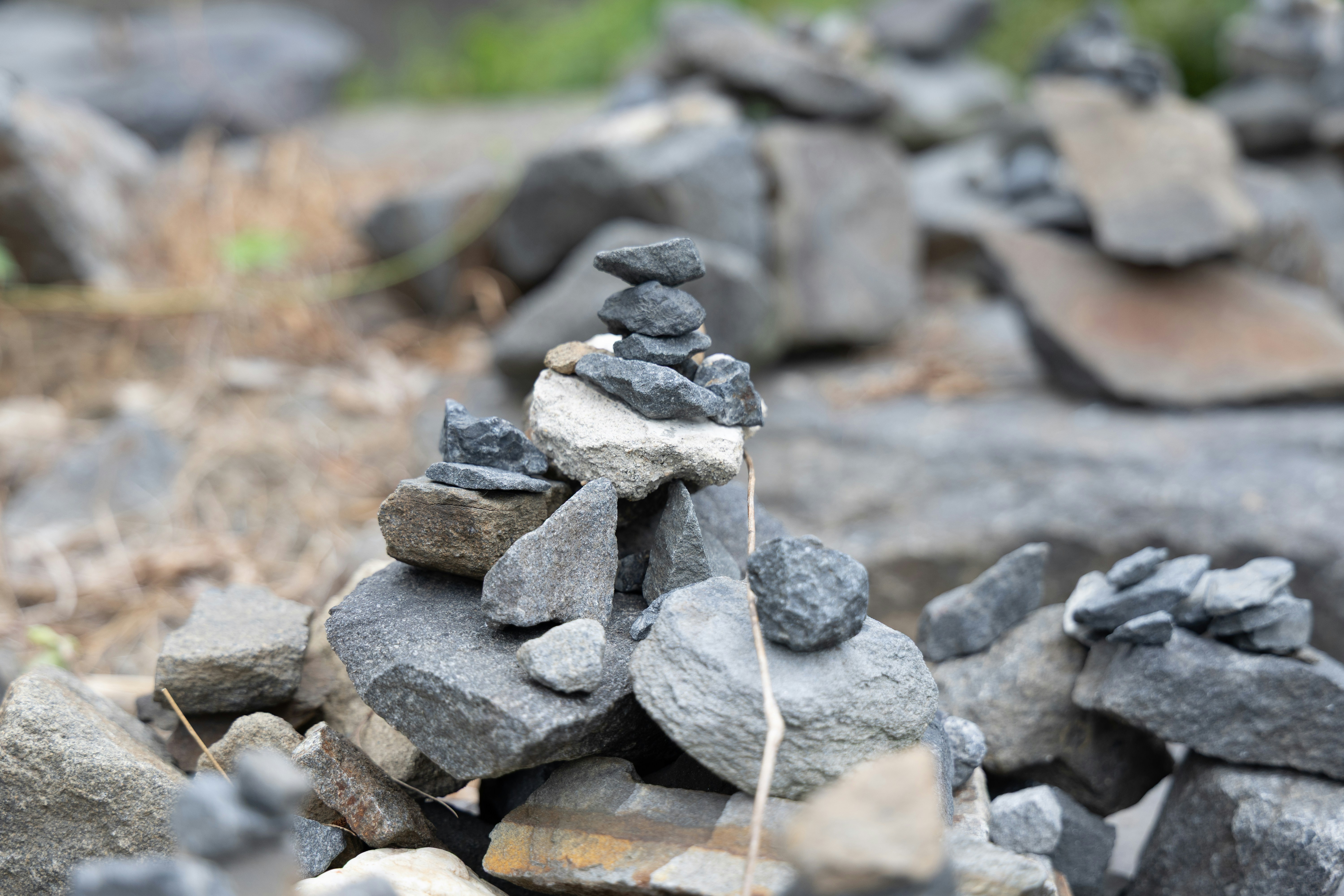 A small stack of balanced grey stones on a rocky ground