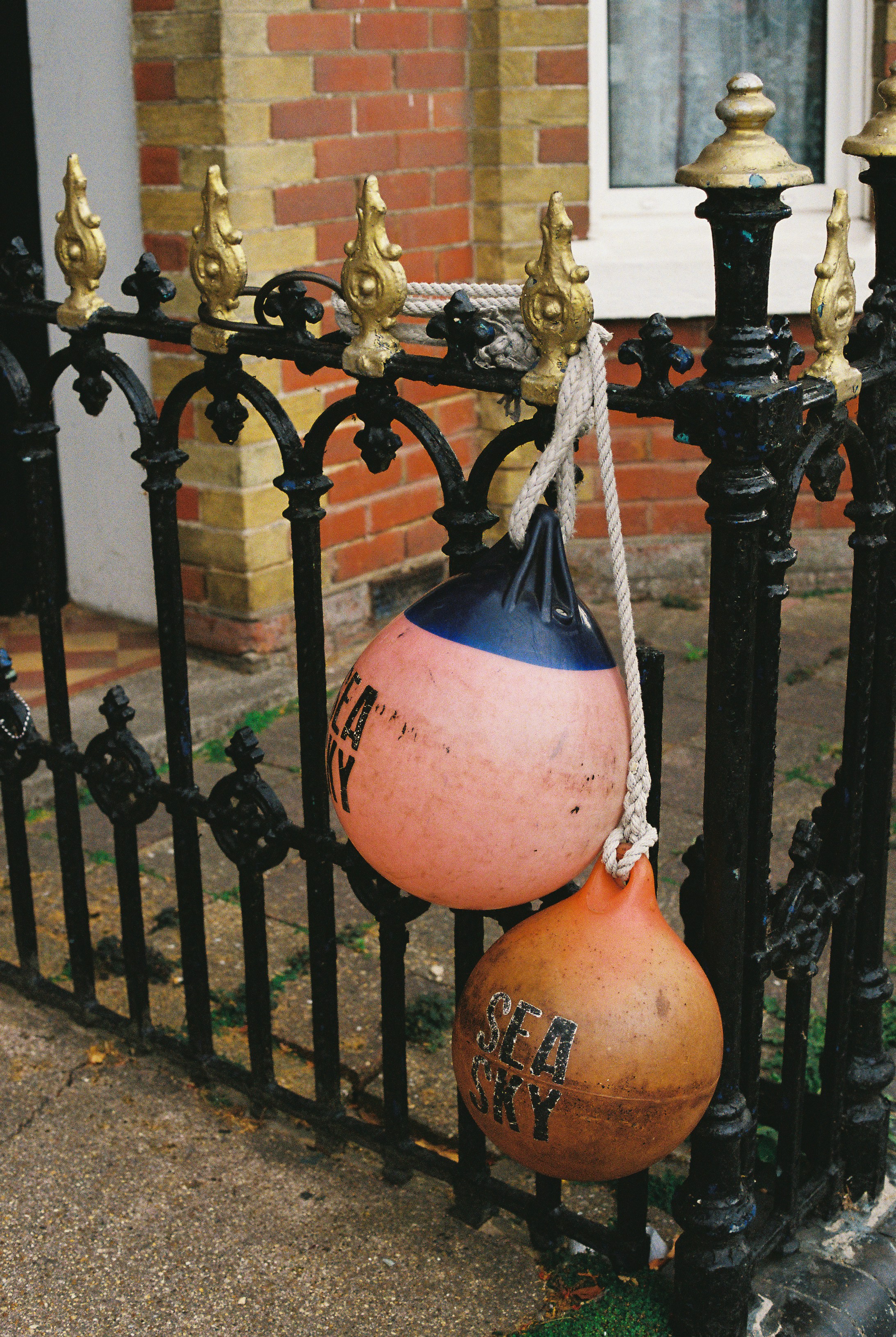 Fotomural Two round nautical buoys hanging from a black iron fence with gold finials