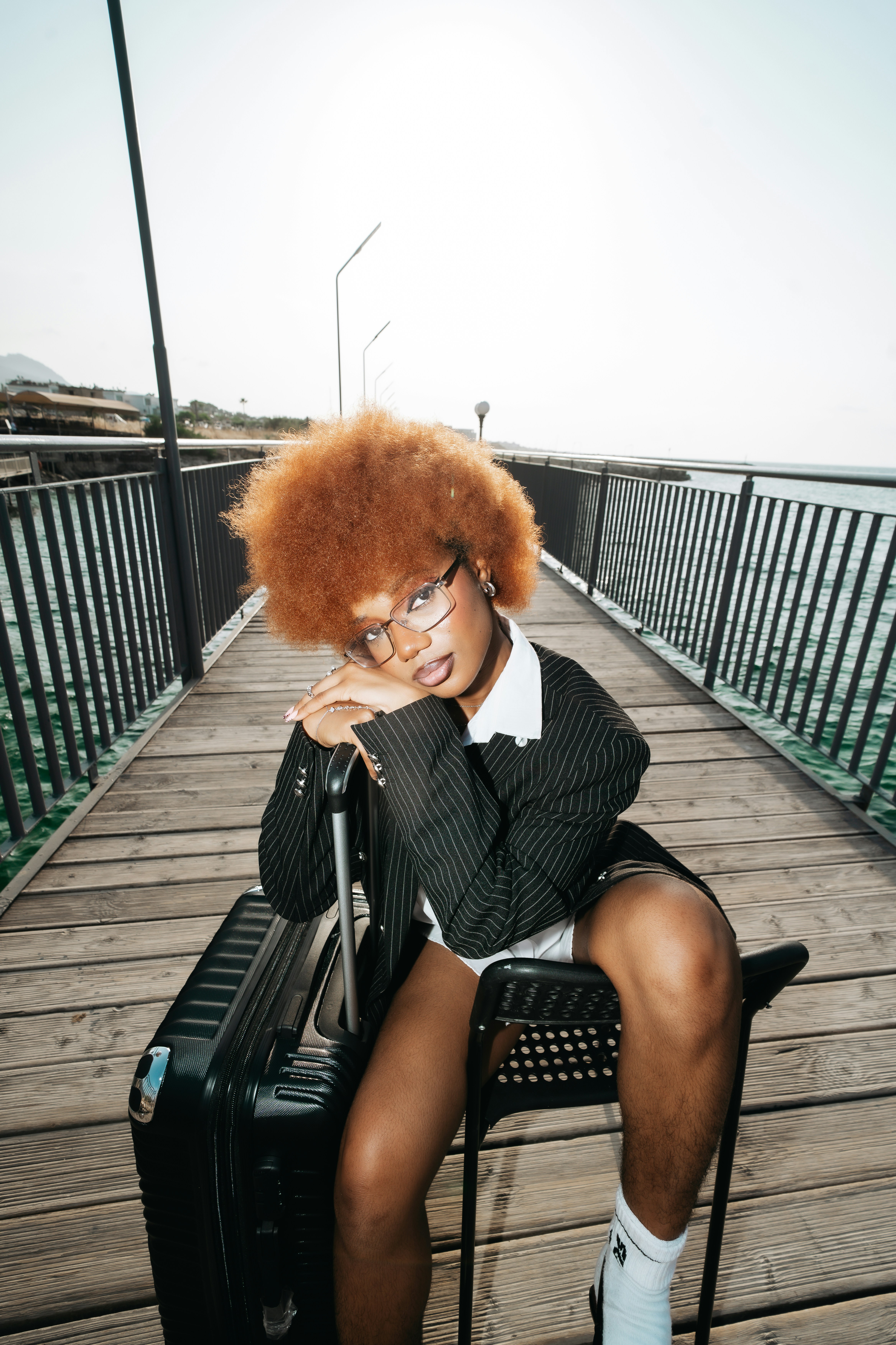 A person with an afro hairstyle wearing a pinstripe blazer on a wooden pier - 相关推荐