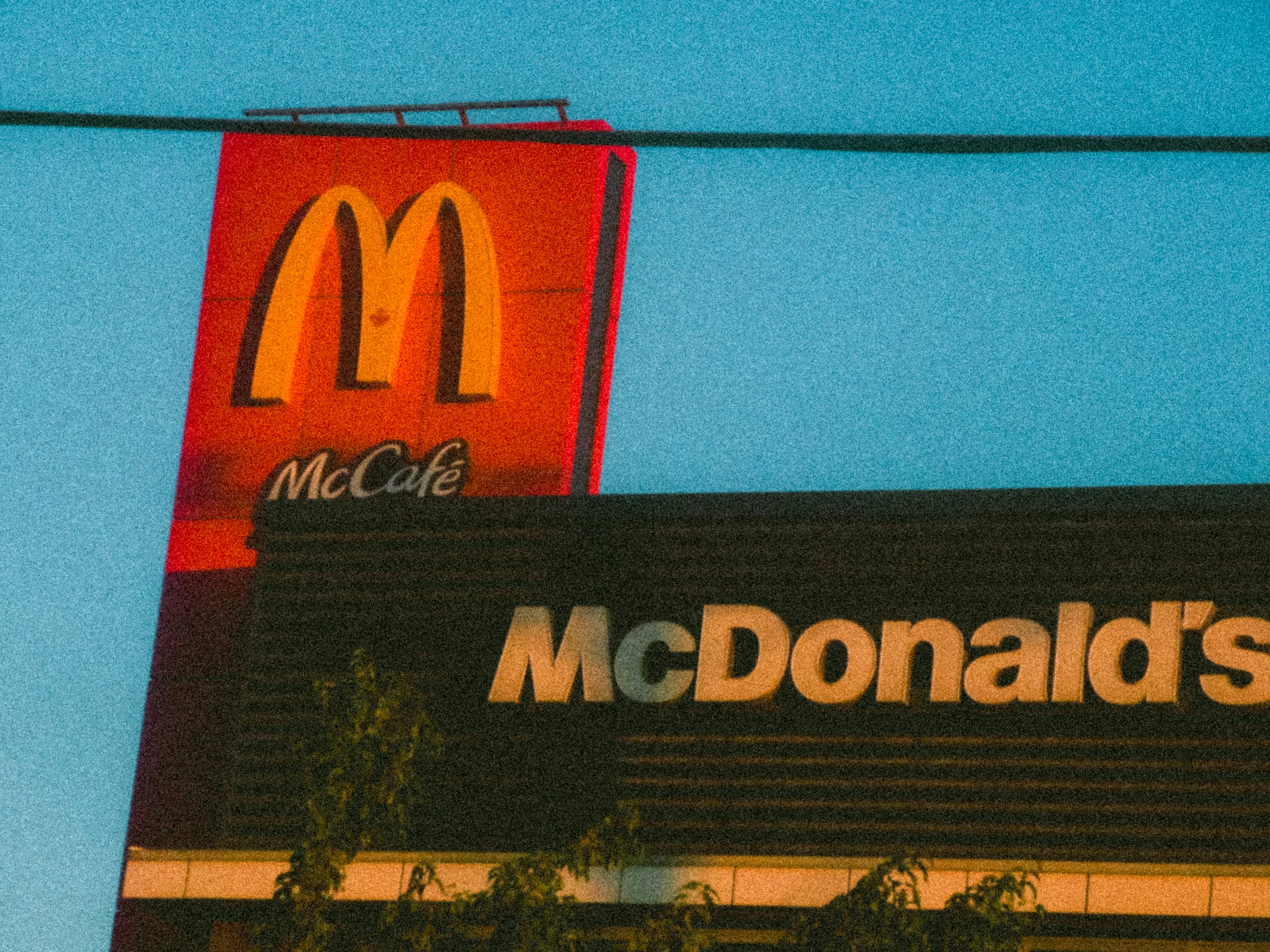 A McDonald's sign with a McCafé logo against a clear blue sky