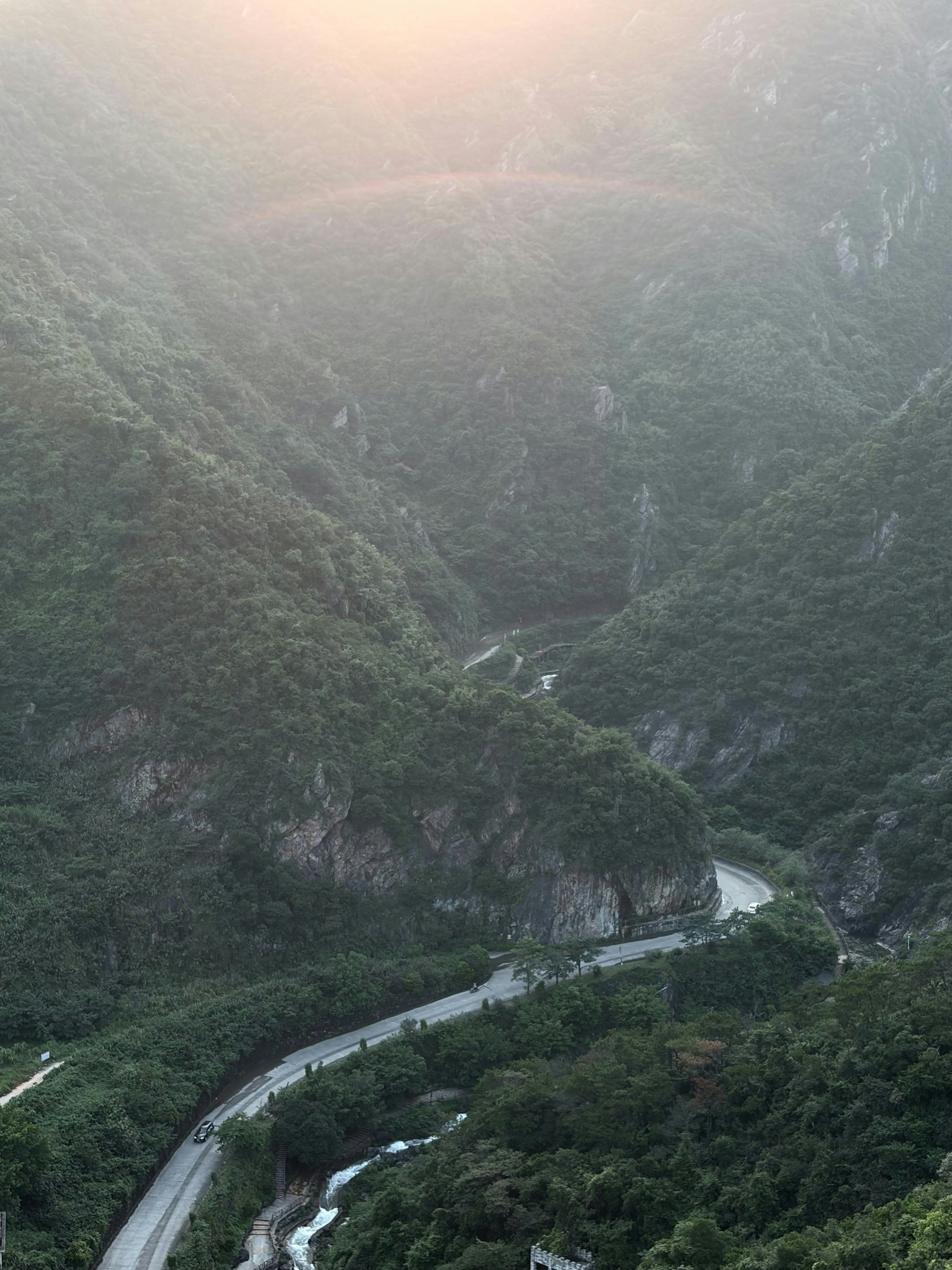 Un camino serpenteante a través de un valle montañoso verde bajo la suave luz de la mañana
