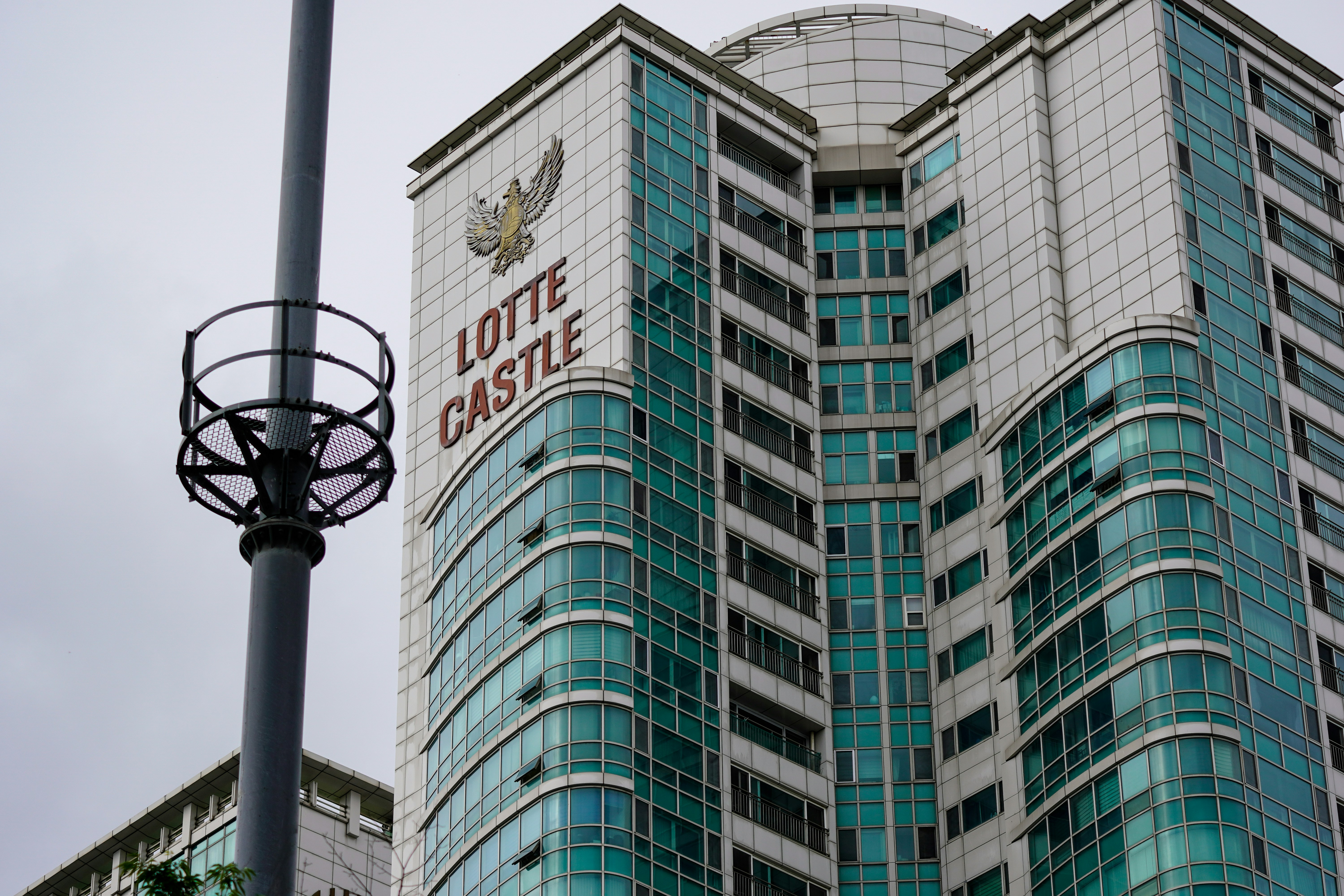 A tall Lotte Castle apartment building with teal glass windows and white panels