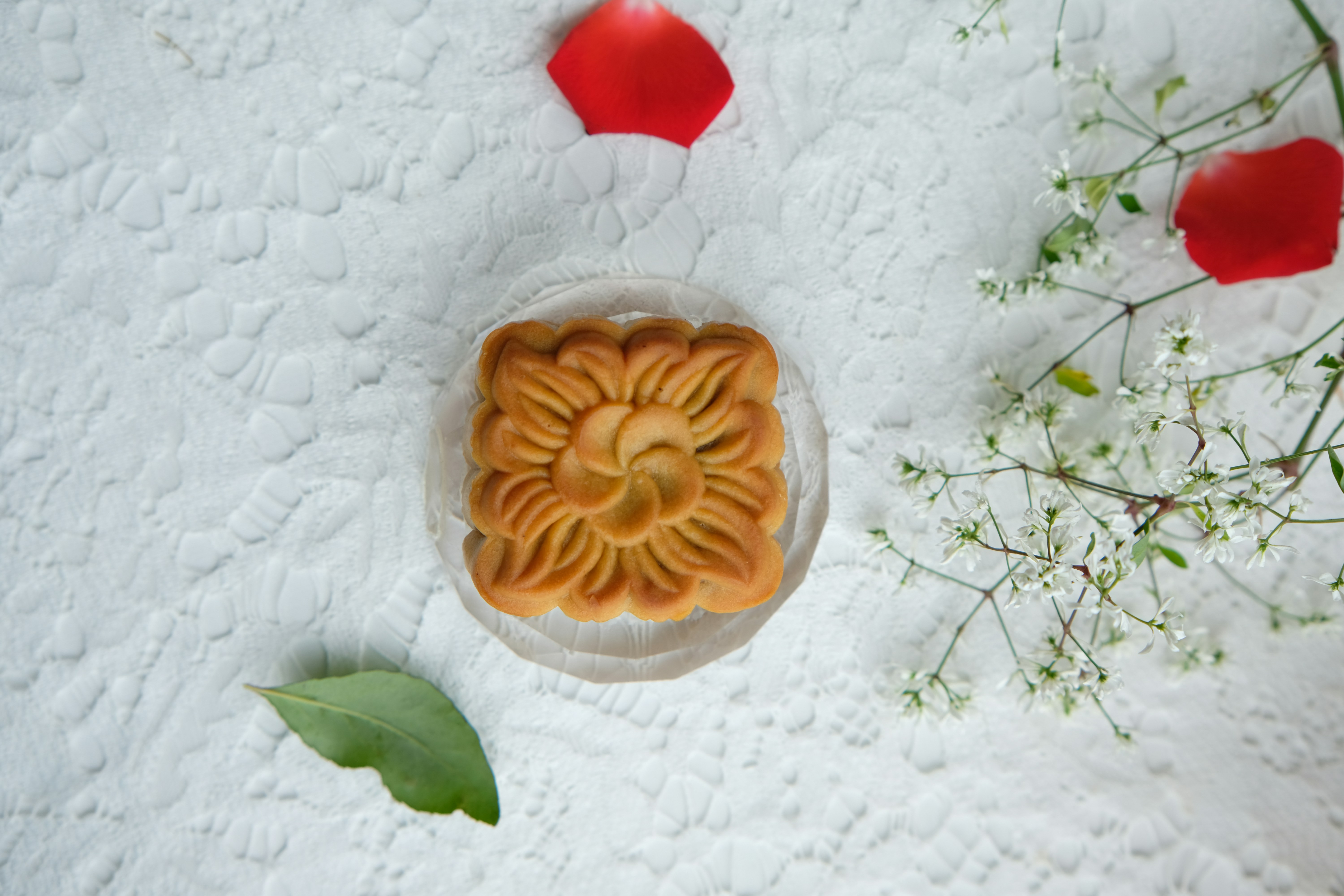 A square mooncake with a floral pattern on a white lace tablecloth