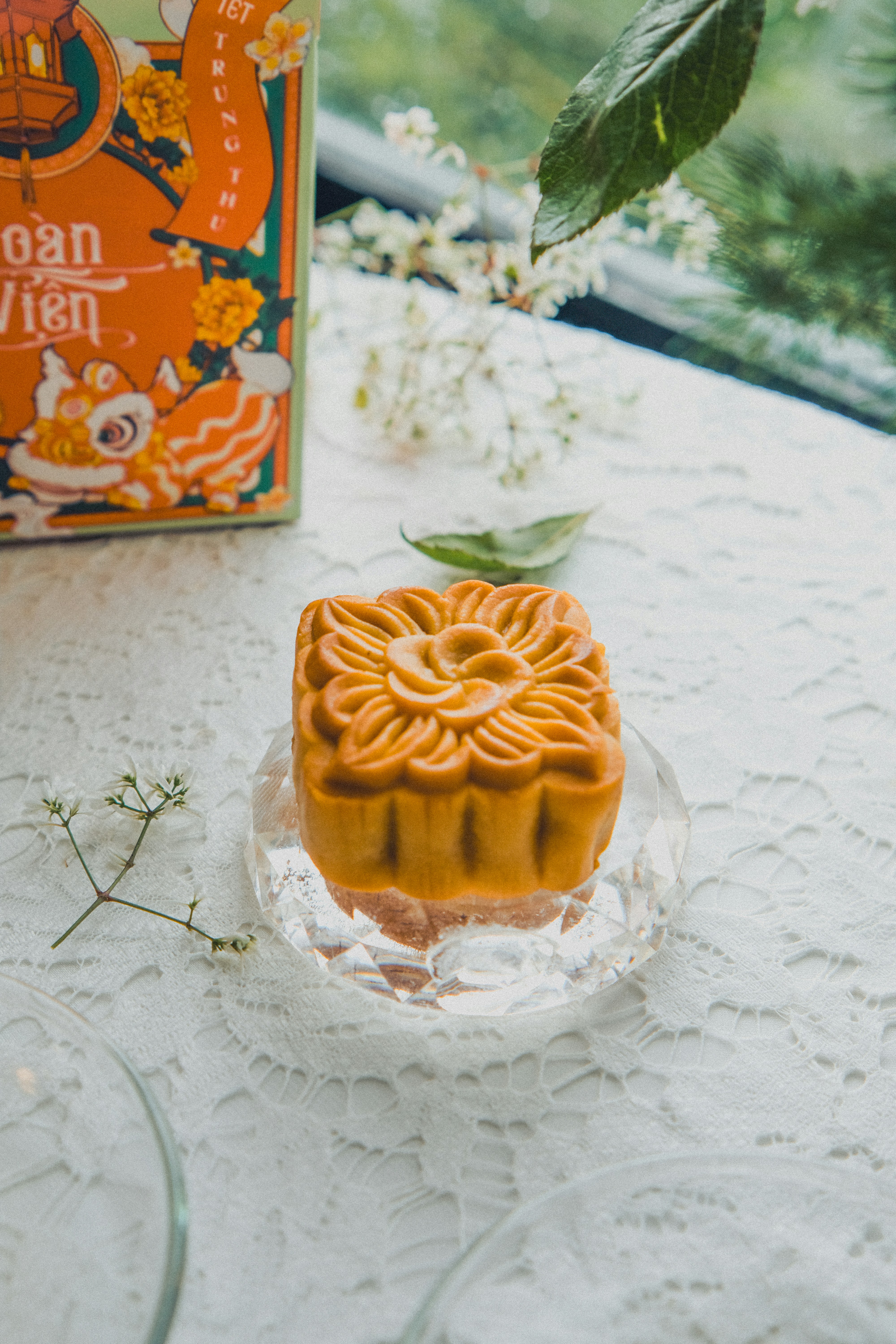 A square mooncake with a floral pattern on a glass plate on lace