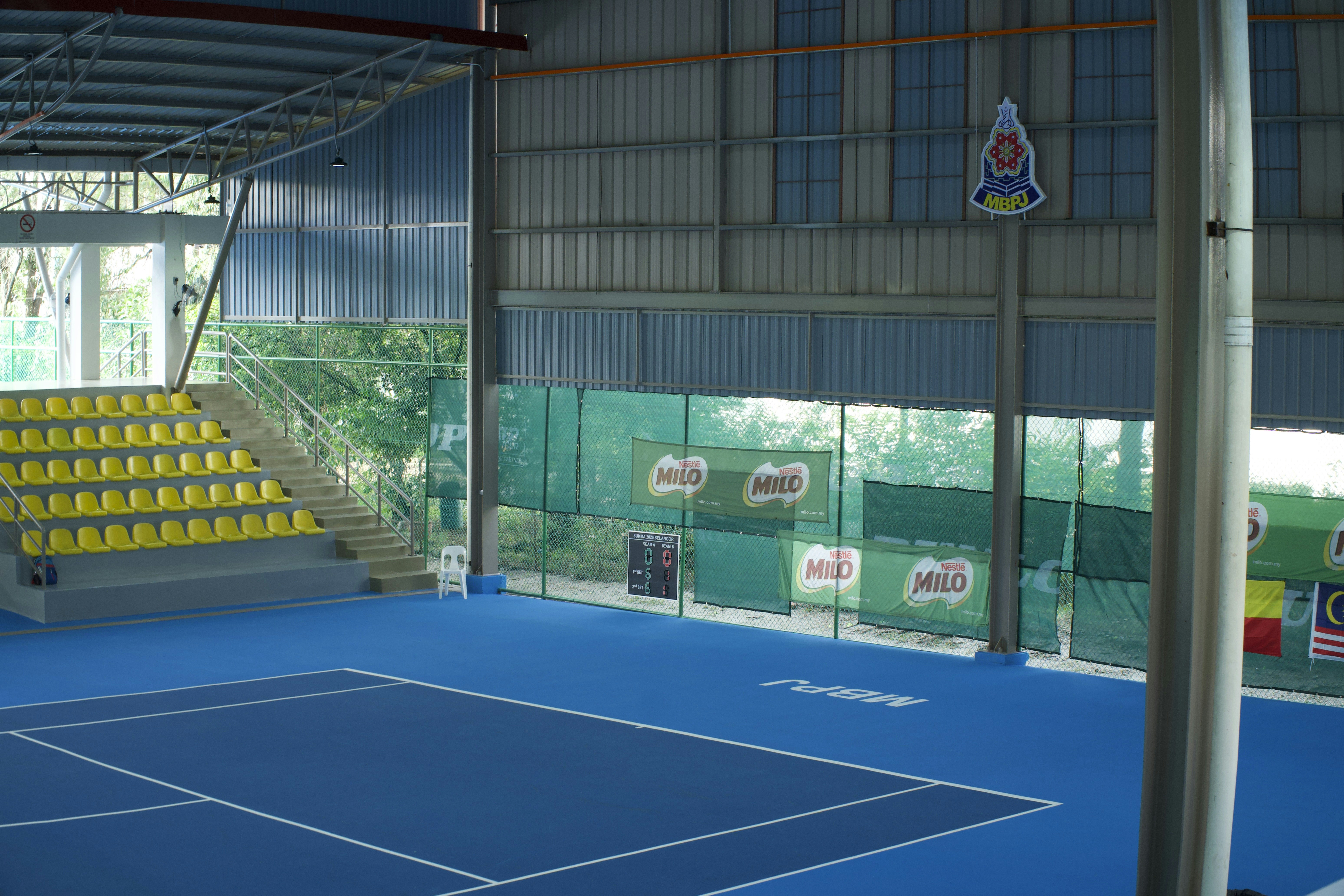 Court de tennis couvert à surface bleue et tribunes jaunes vides, comme les salles du Heysel avant l'European Open 2026