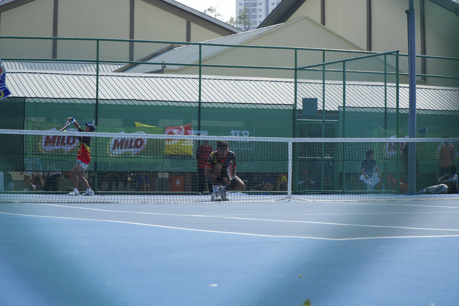 Two tennis players on a blue court with a green chain-link fence