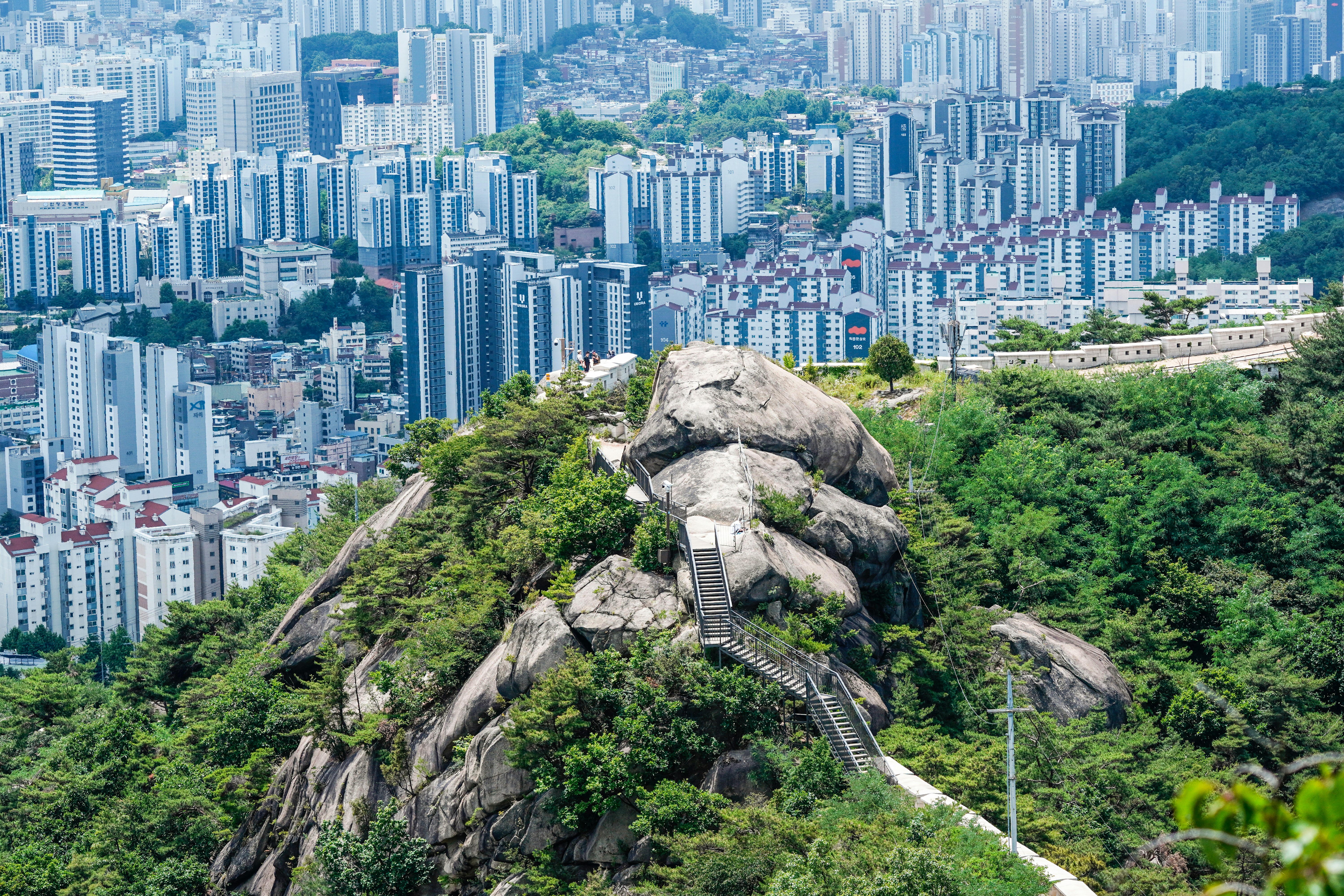 A metal staircase winding up a rocky mountain peak overlooking a dense city