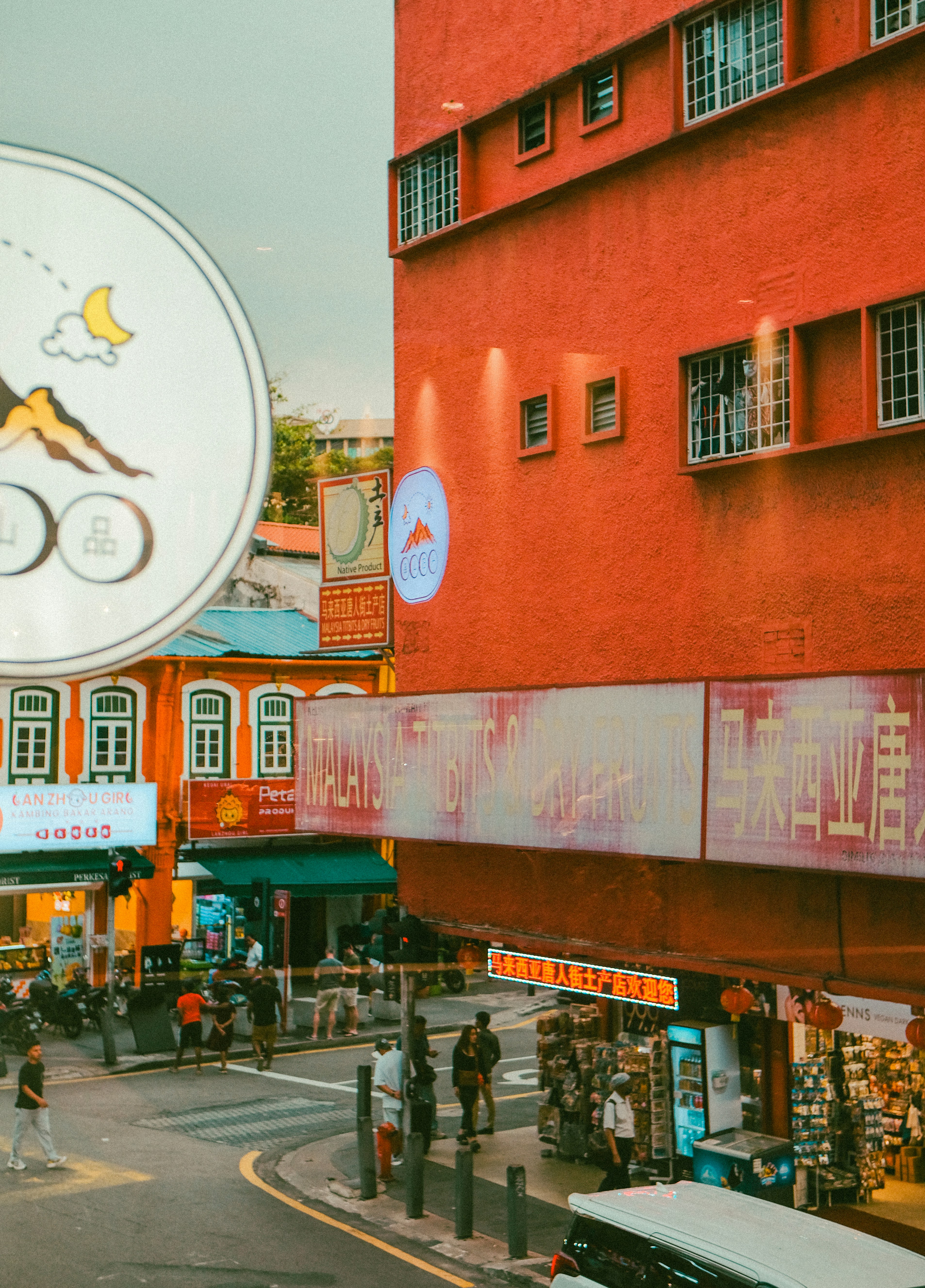 People walking on a street lined with orange buildings and shopfronts in Kuala Lumpur