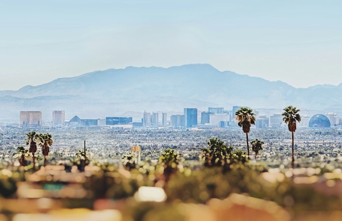 The Las Vegas skyline with palm trees in front and mountains behind, home to the families who feel state budget choices most