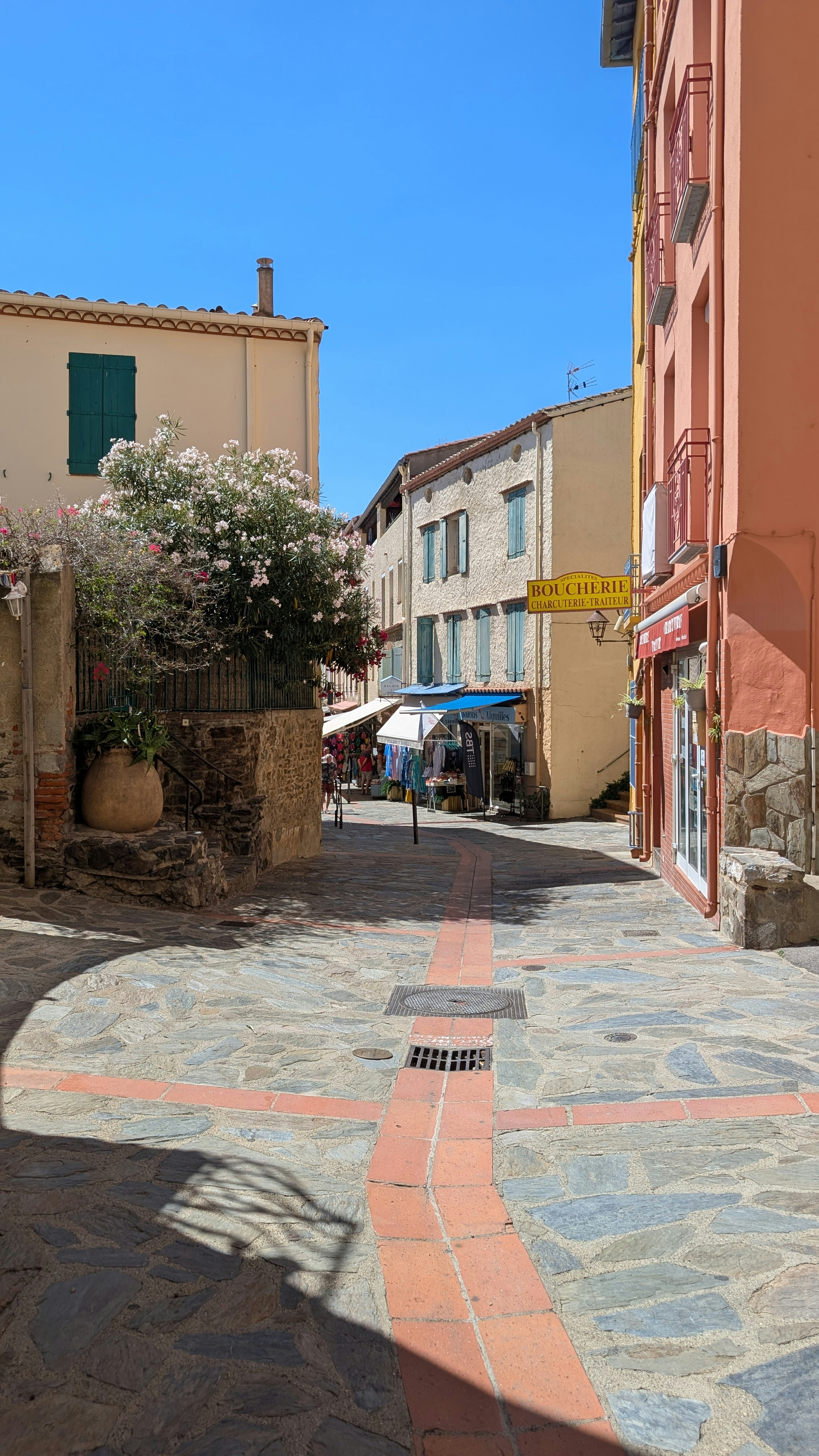 A narrow cobblestone street in a French village with a butcher shop sign