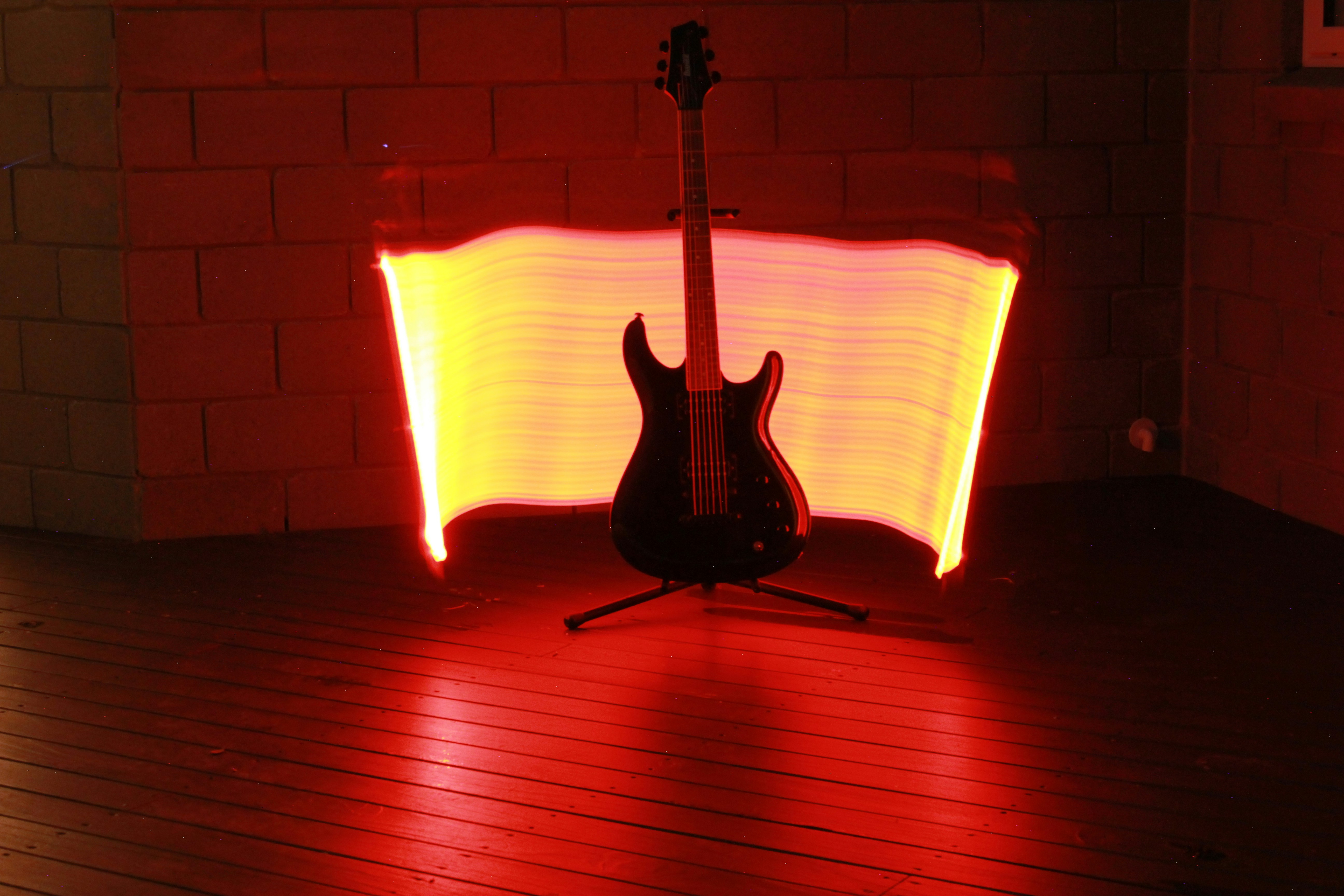 A black electric guitar on a stand against a long exposure light trail