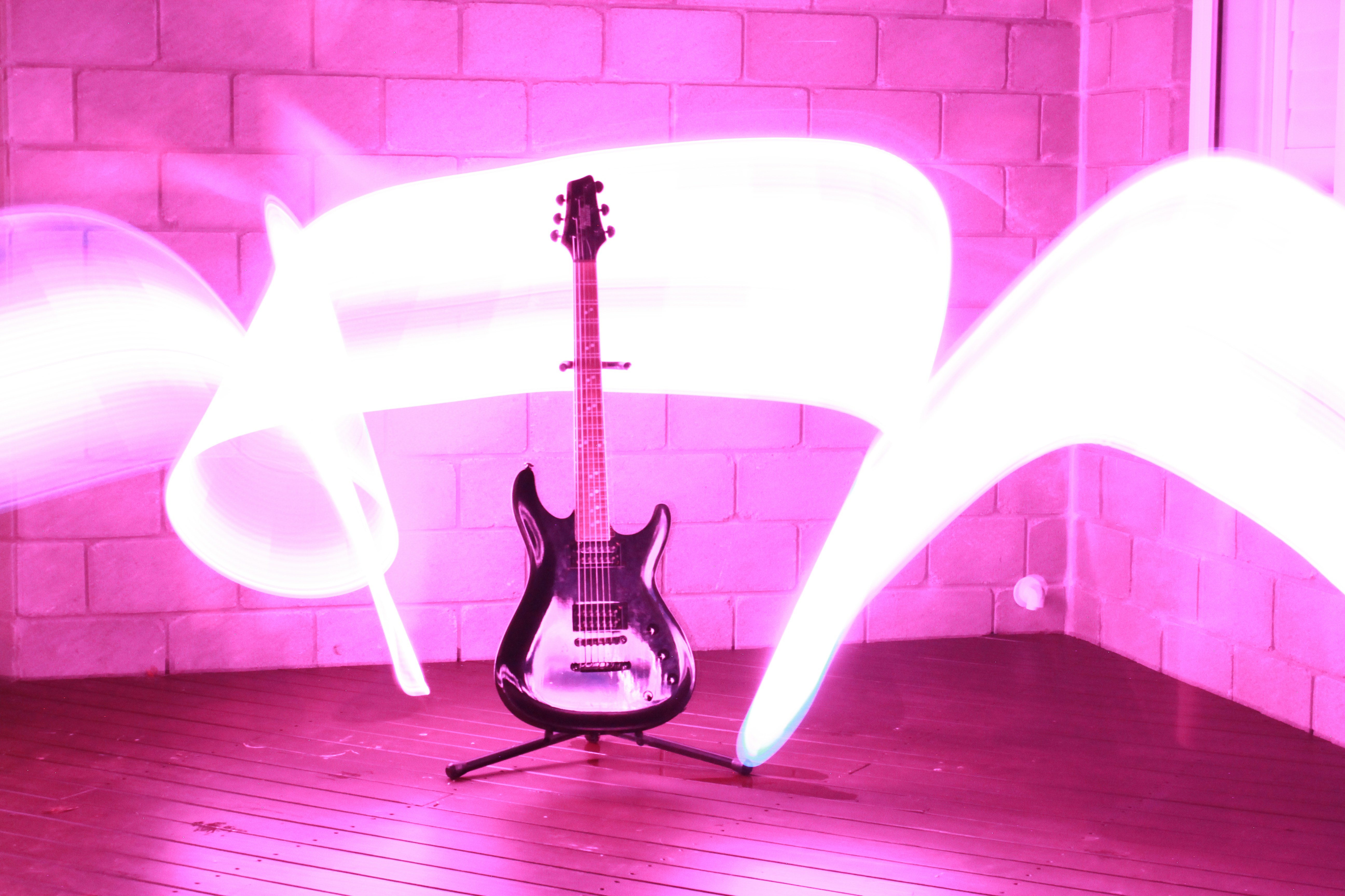 An electric guitar on a stand with long exposure pink light trails