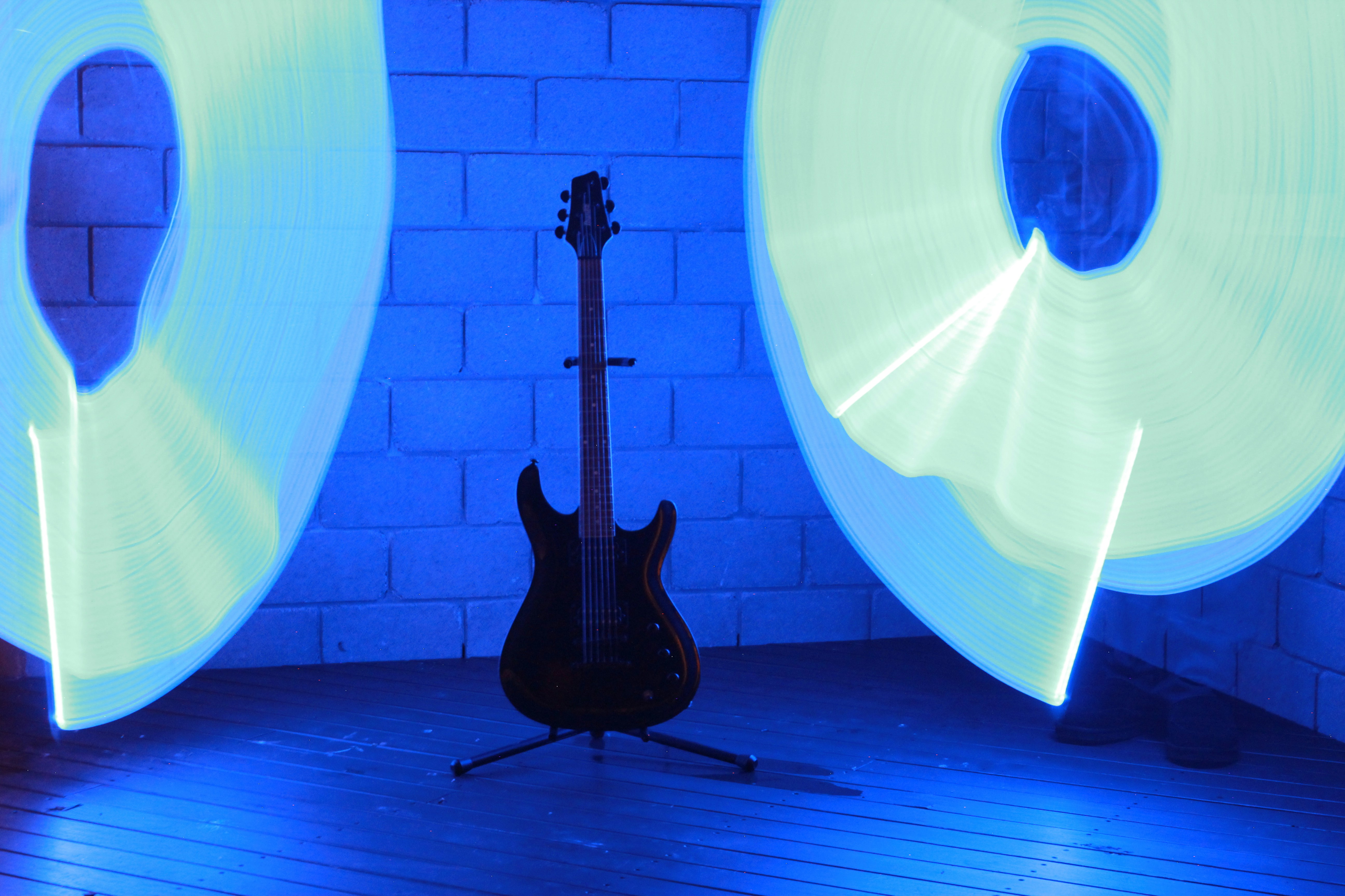 An electric guitar on a stand between two glowing light trails in blue