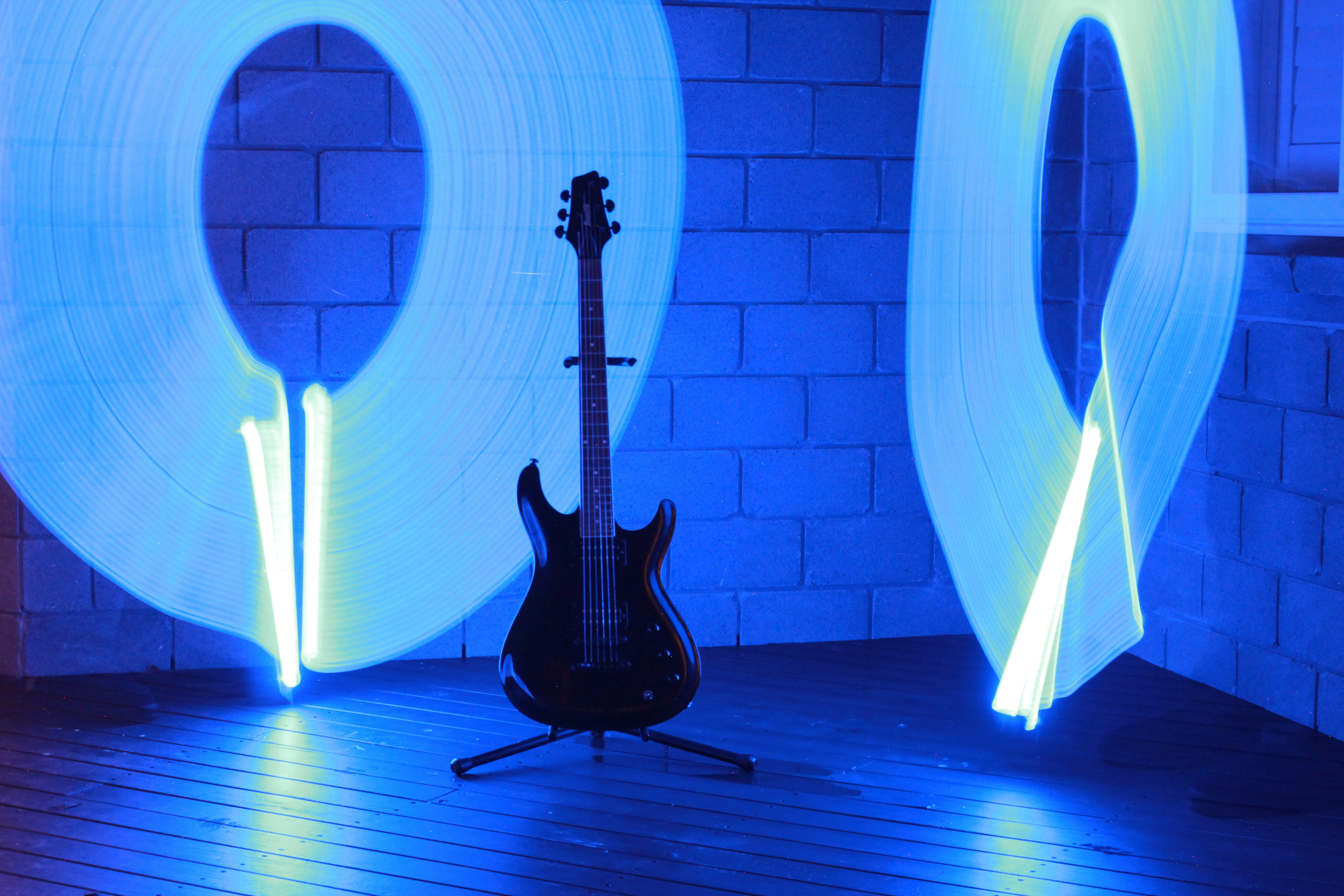 An electric guitar on a stand before blue light painting circles