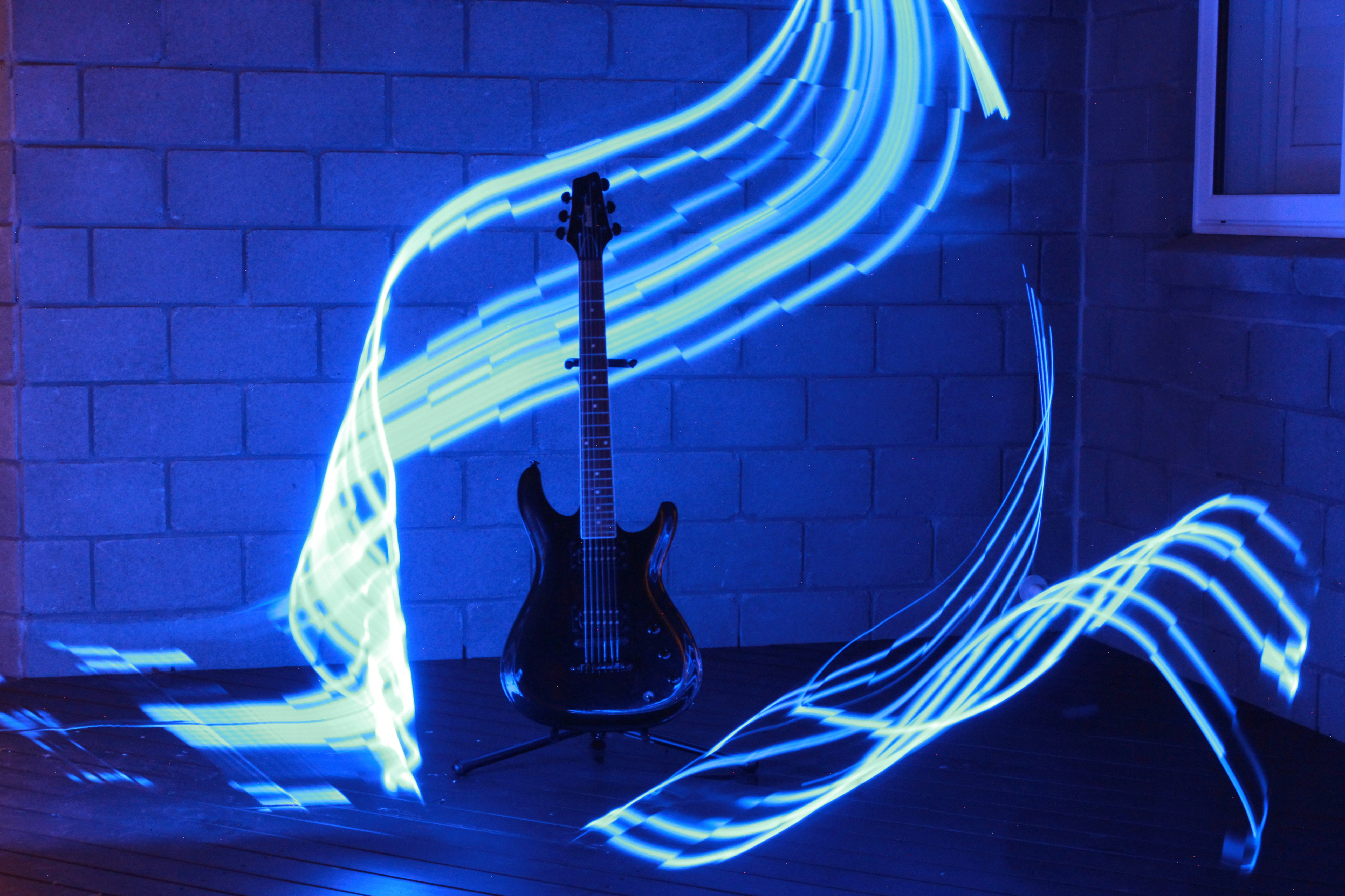 A black electric guitar on a stand with blue light painting trails
