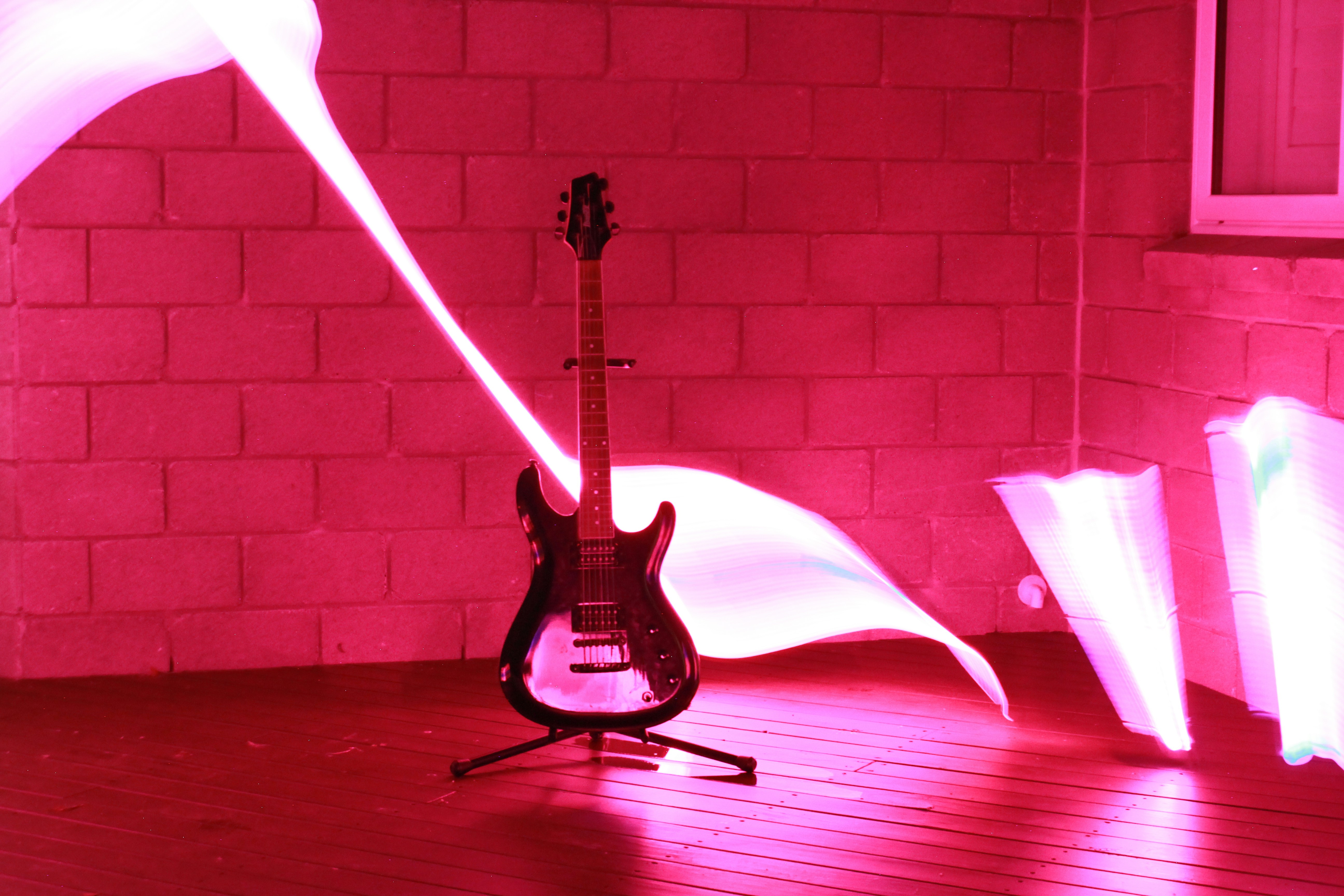 An electric guitar on a stand with long exposure light trails in pink