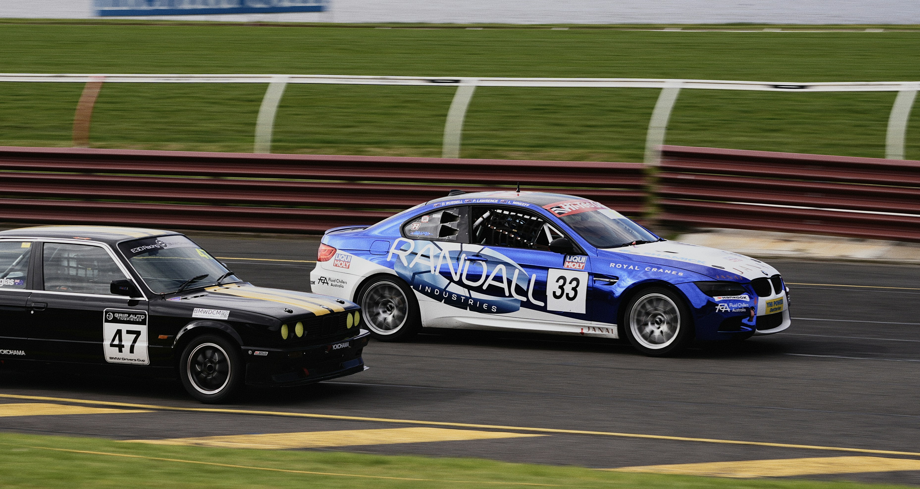 A black BMW and a blue and white BMW racing on a track