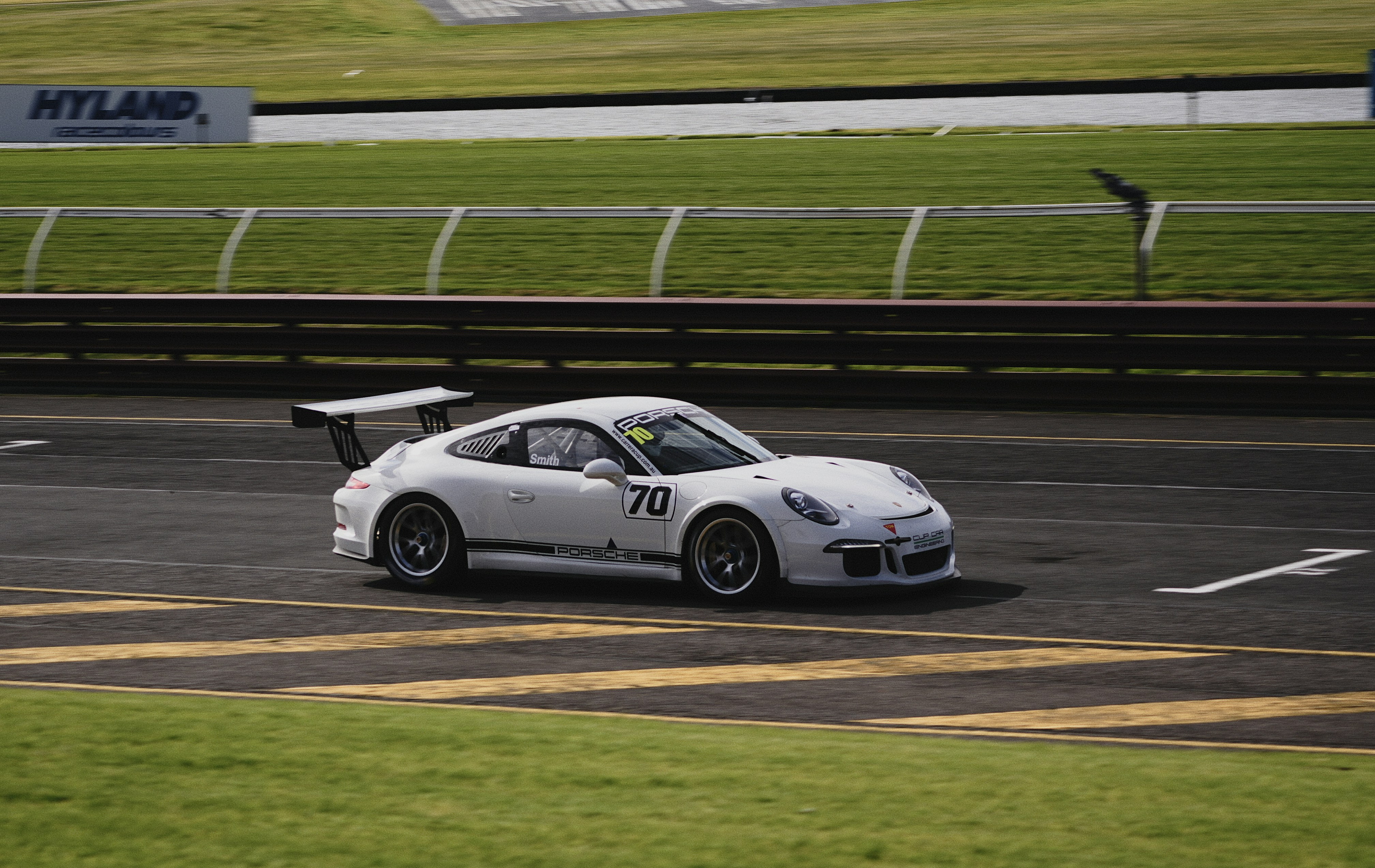 A white race car with number 70 driving on a paved track