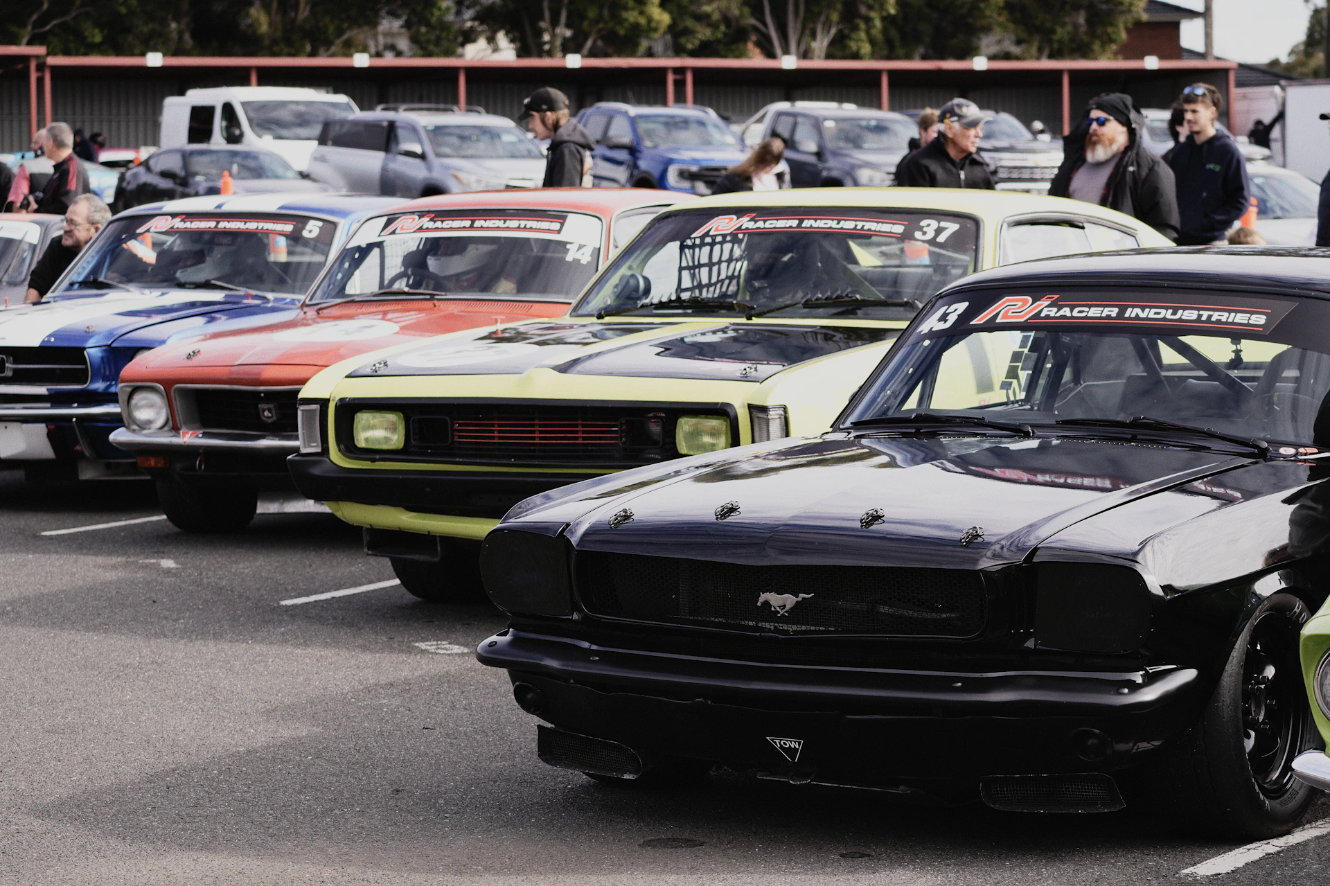 A row of colorful vintage race cars parked in an asphalt lot