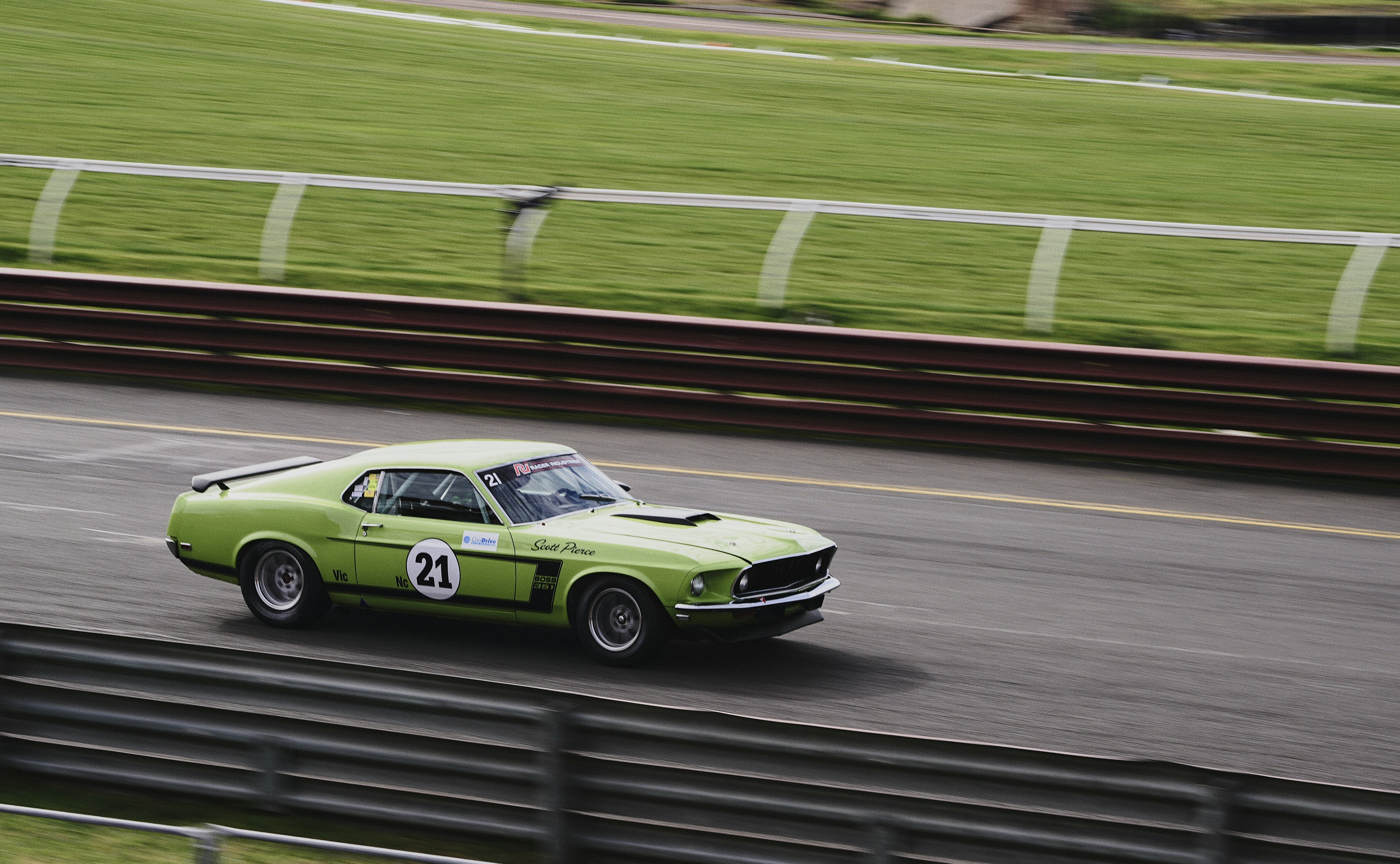 A lime green vintage race car with the number 21 on a track