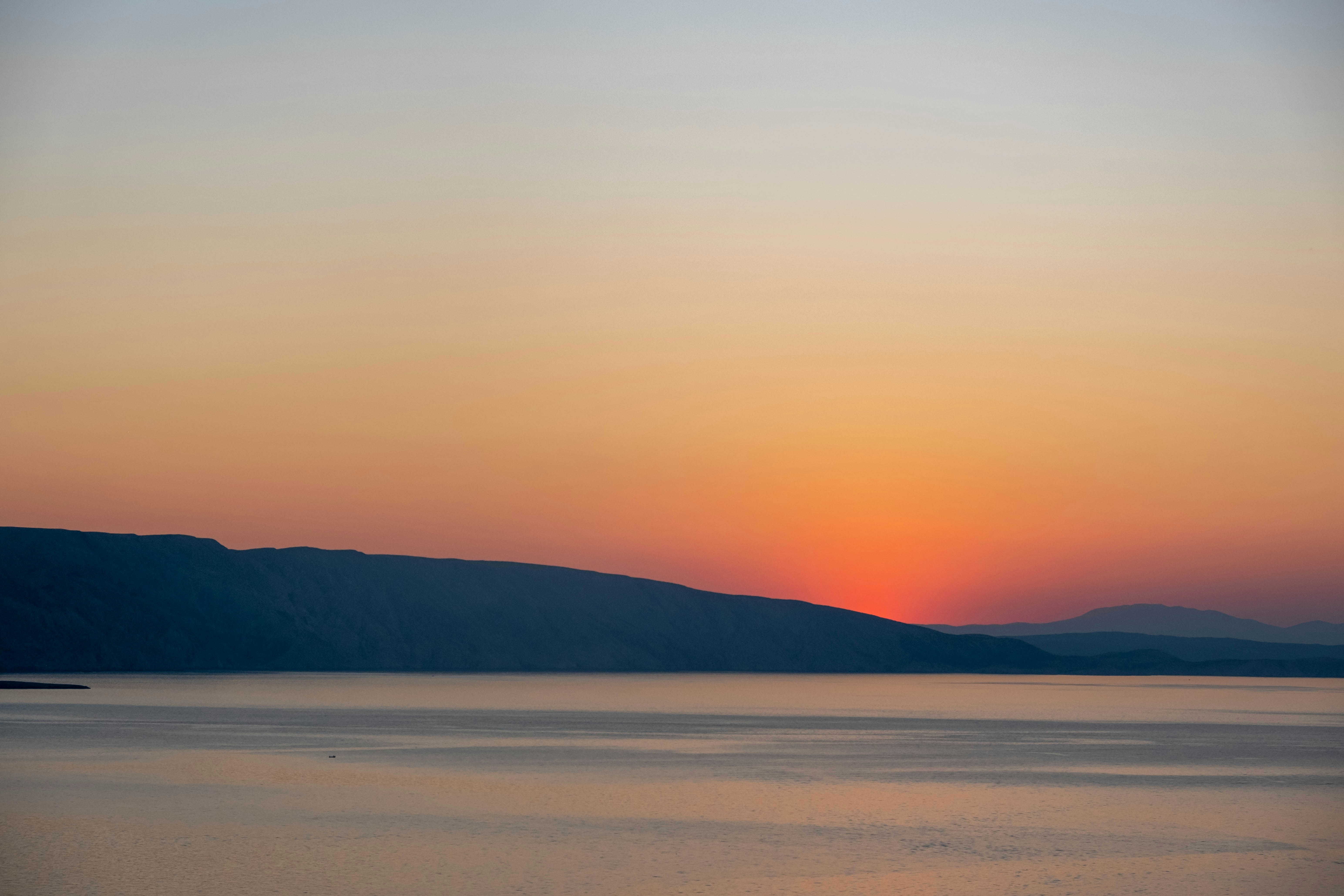 Mountain silhouette over calm water - Free Photo on Unsplash