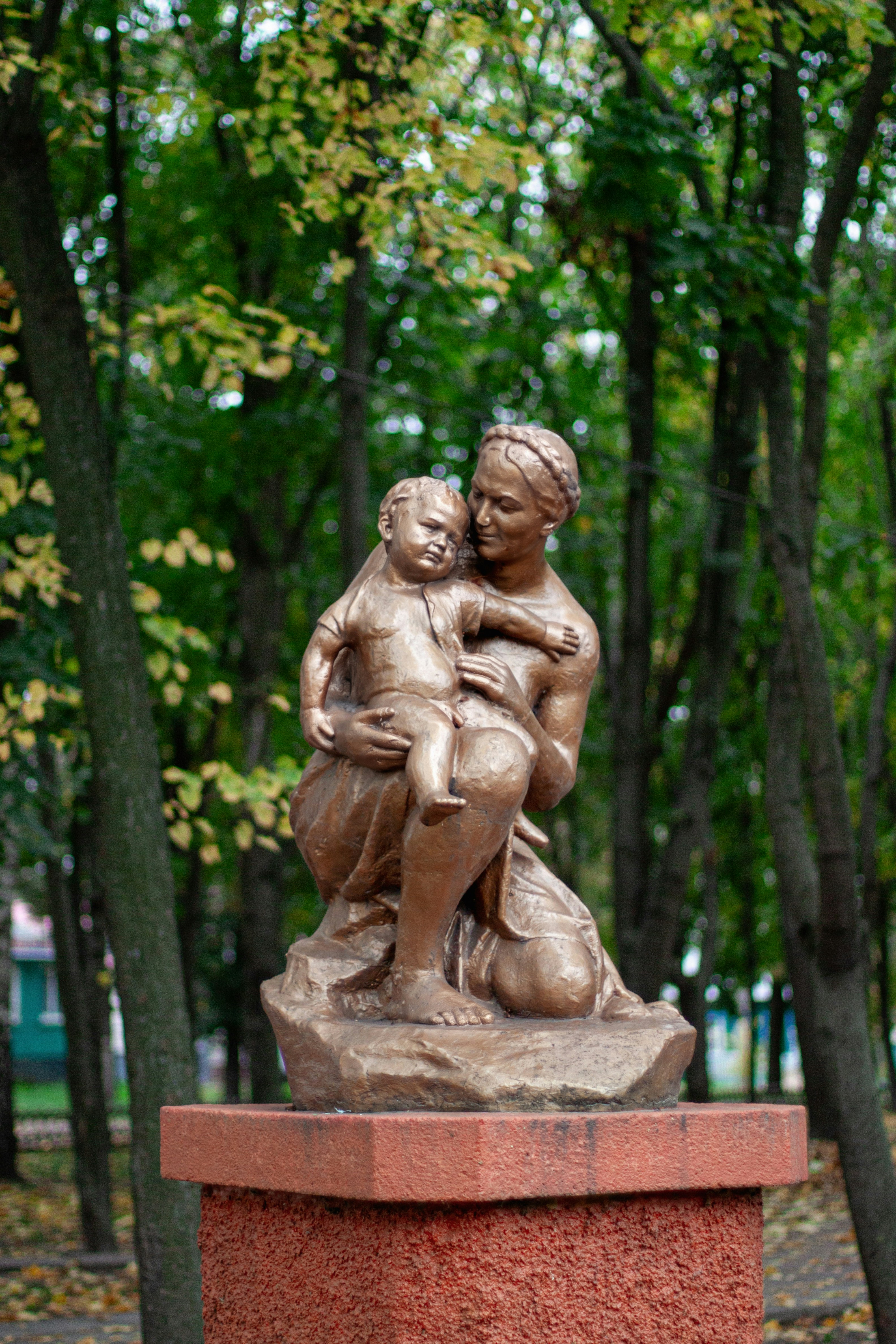 A bronze statue of a woman holding a child in a park