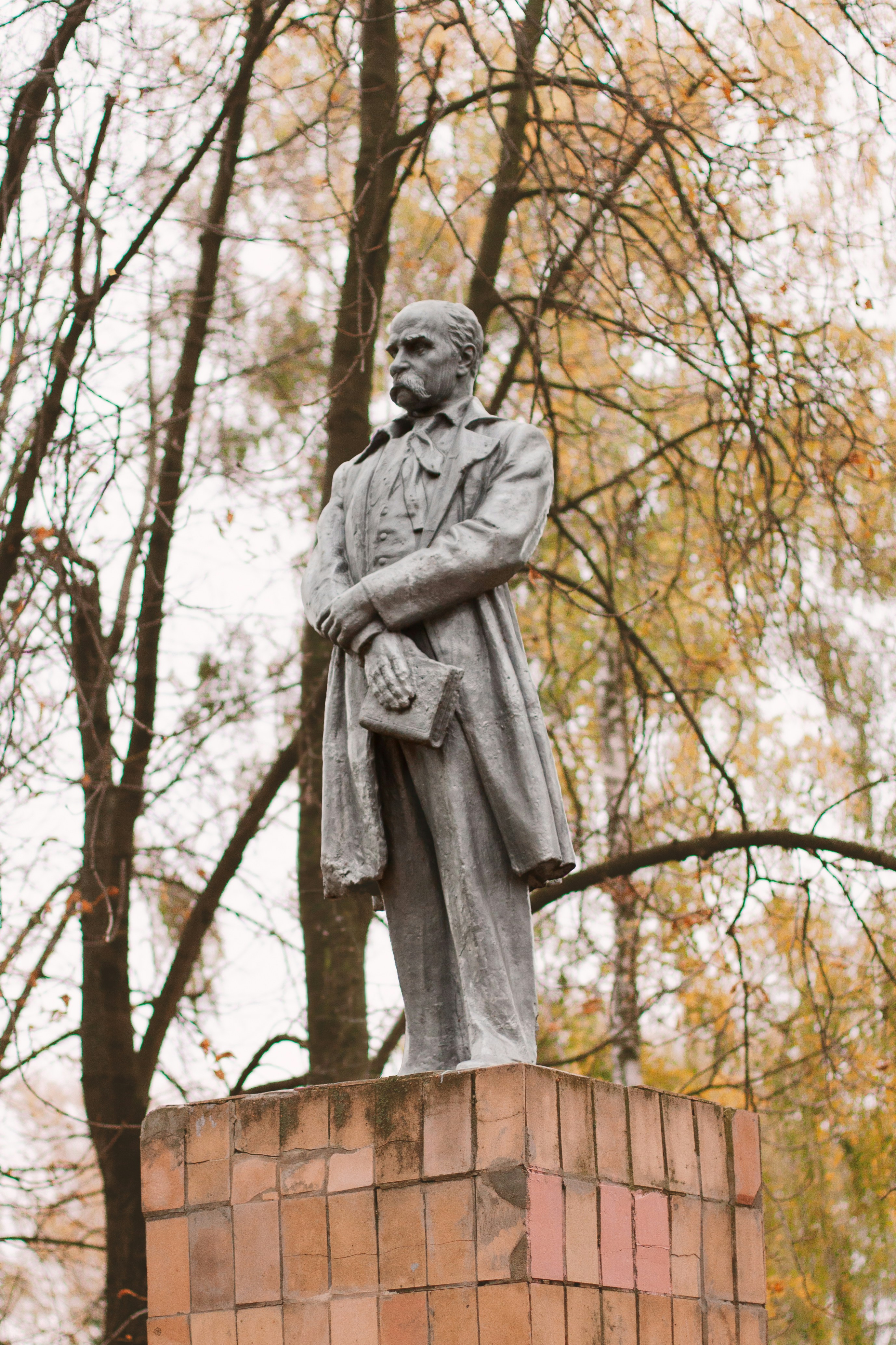 A stone statue of a man with a mustache holding a book outdoors