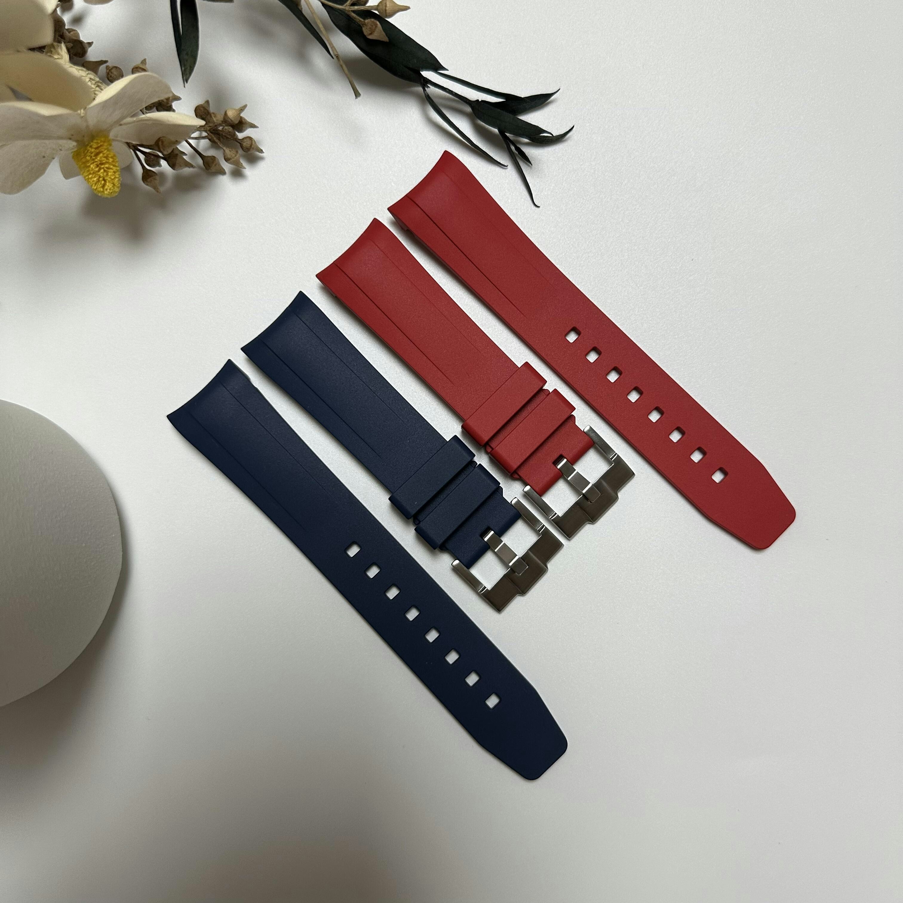 A red and a blue rubber watch strap on a white surface