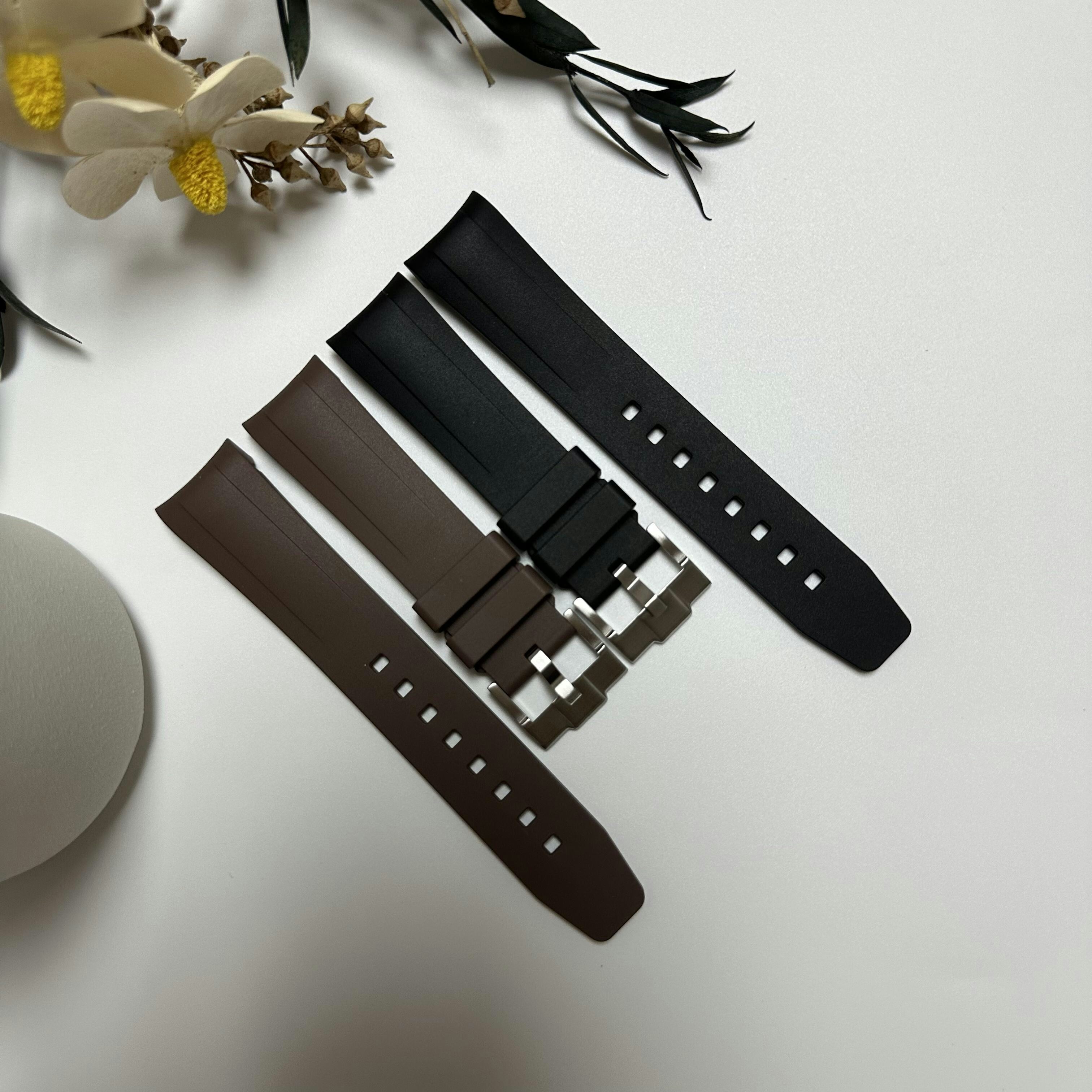 A black and a brown rubber watch strap on a white surface