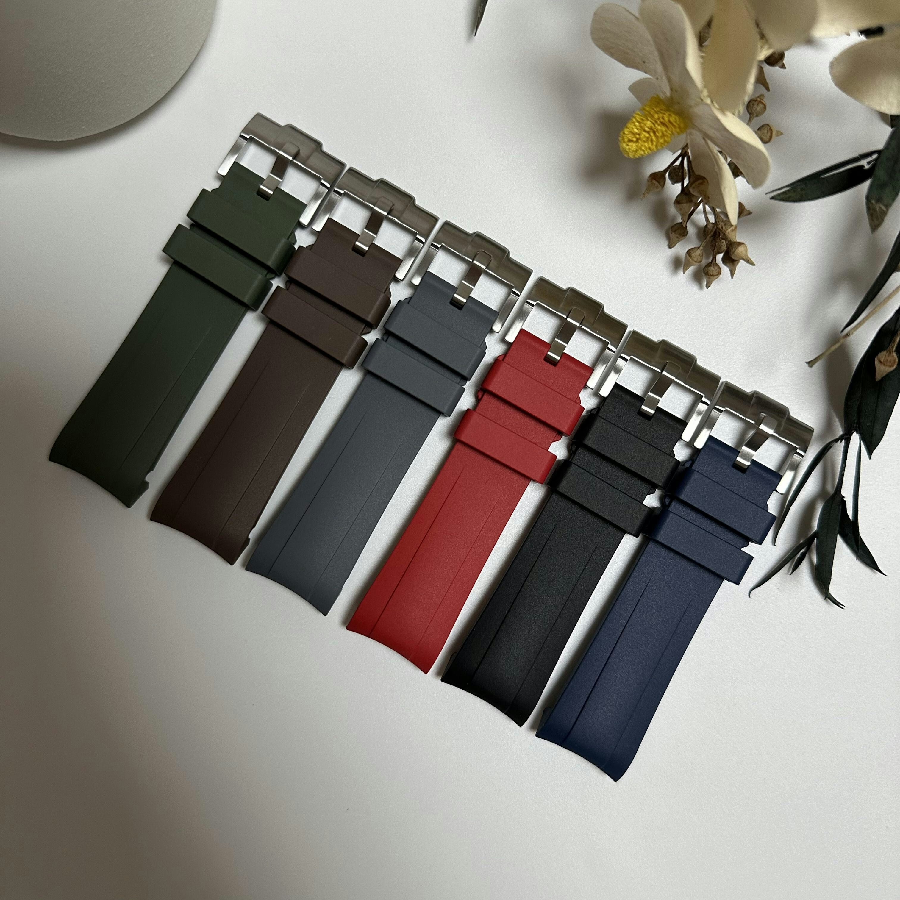 Six colorful silicone watch straps with metal buckles arranged on a white surface
