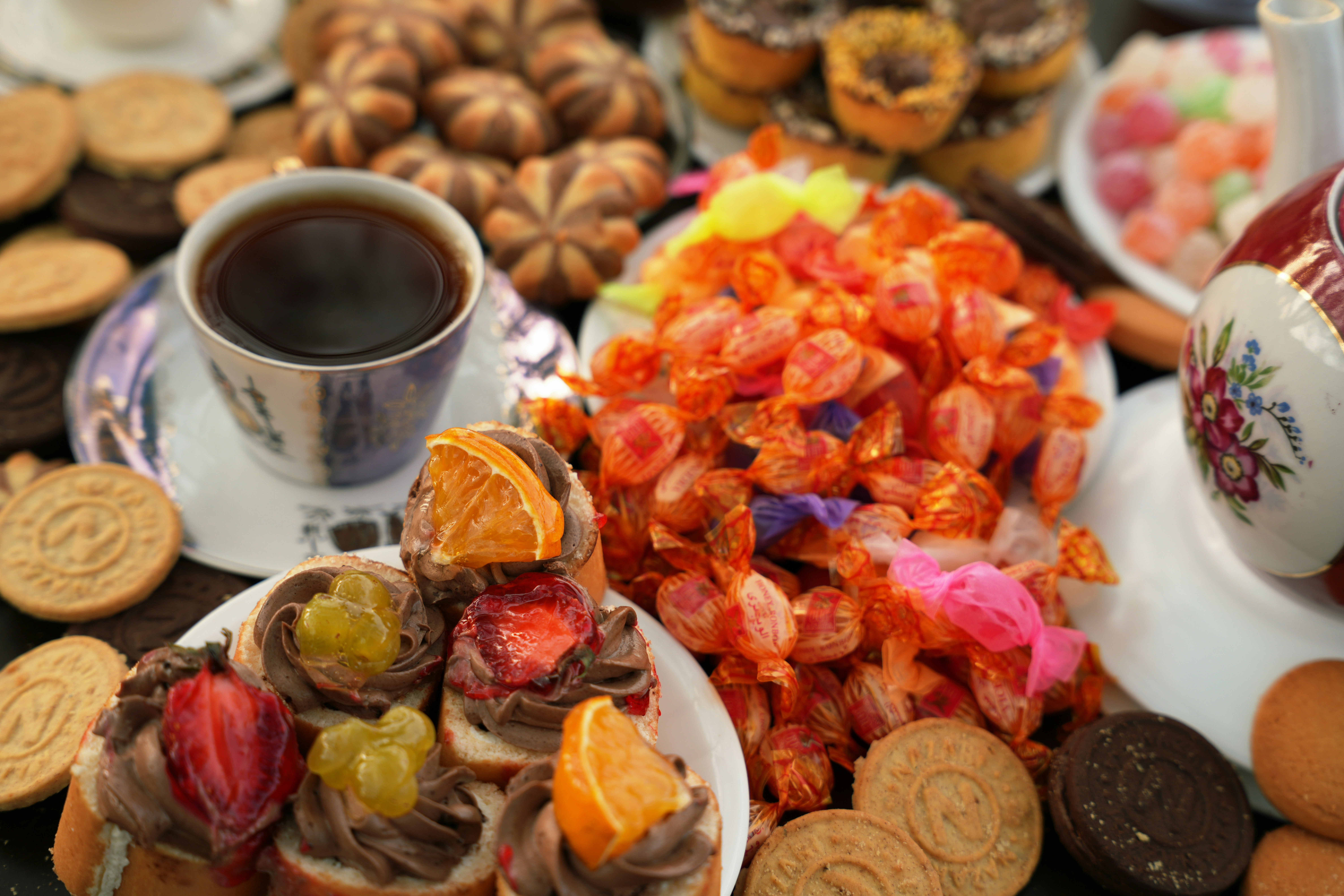 A cup of coffee with assorted cookies, candies, and chocolate topped pastries