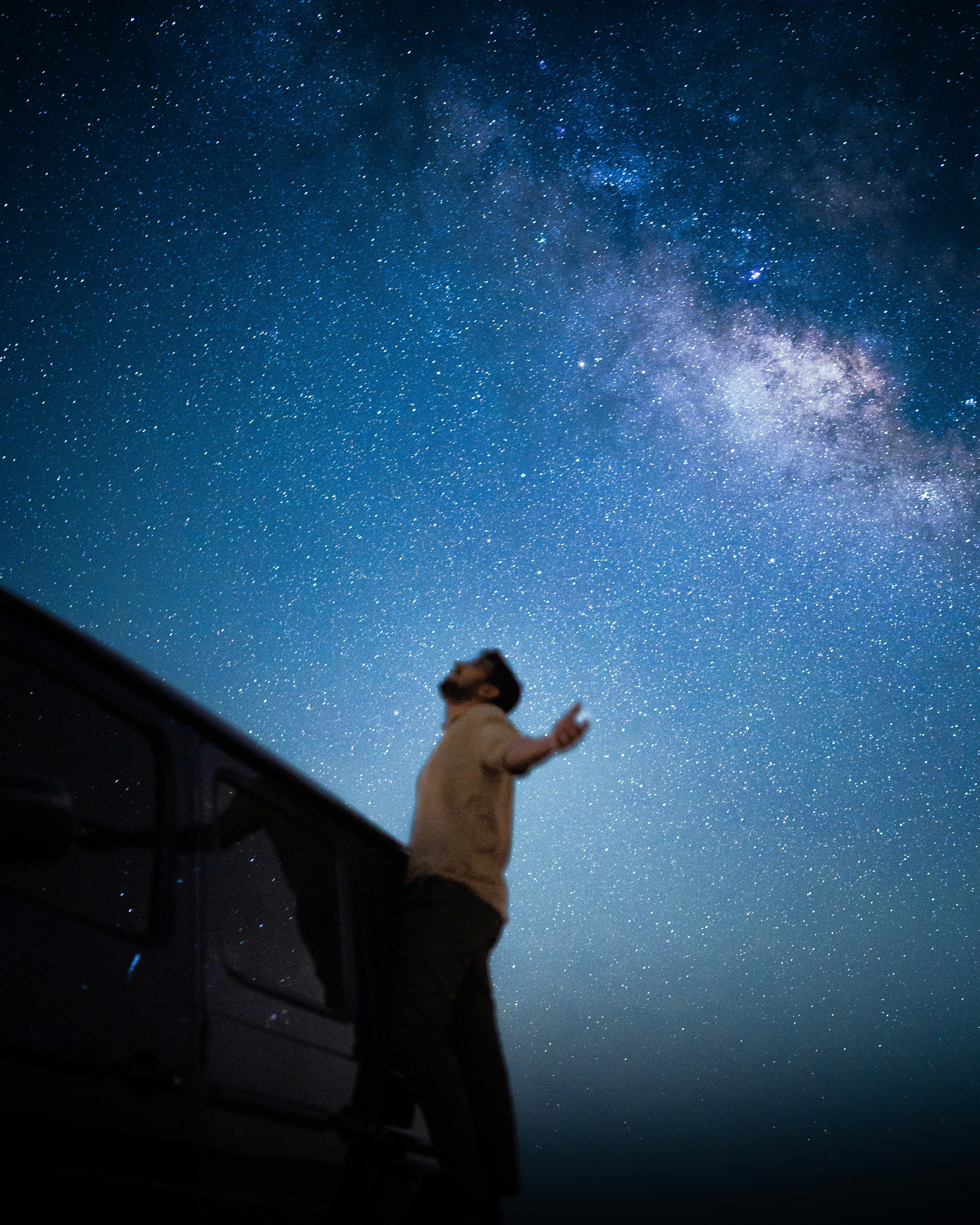 A person with arms outstretched beside a vehicle under a starry night sky - 相关推荐