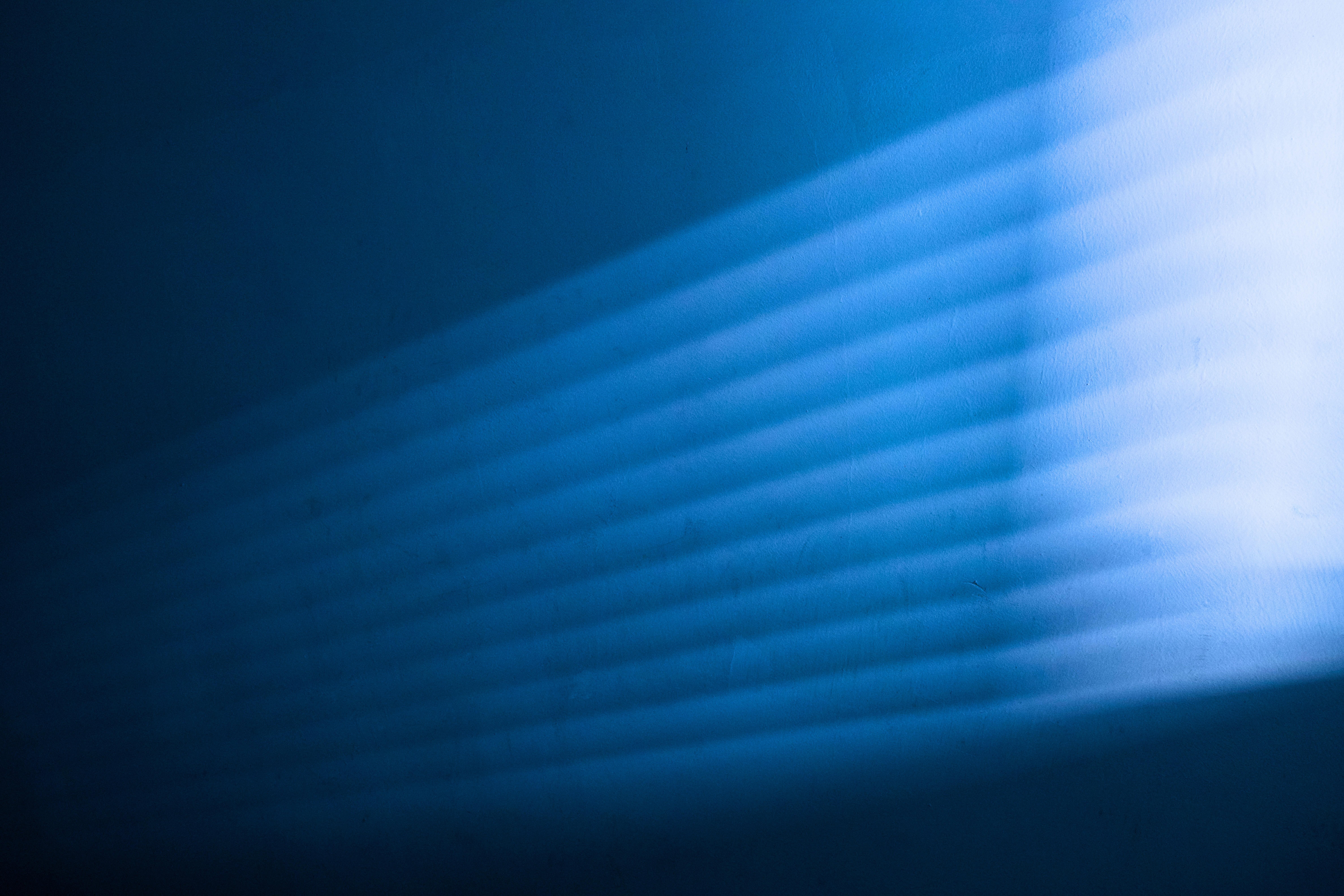 Des bandes parallèles de lumière projetées sur un mur bleu foncé