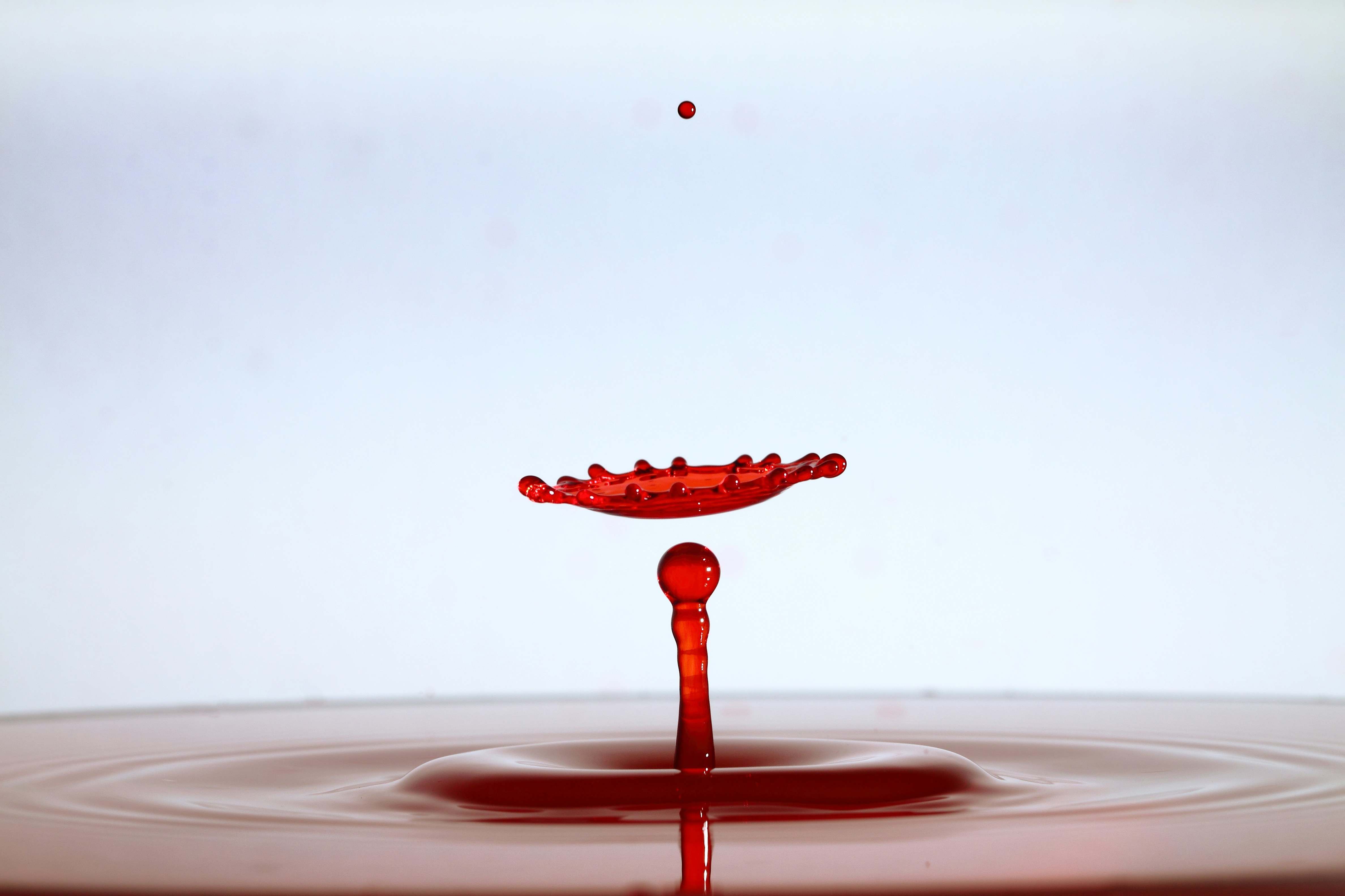 A red liquid drop creating a crown splash above a central column