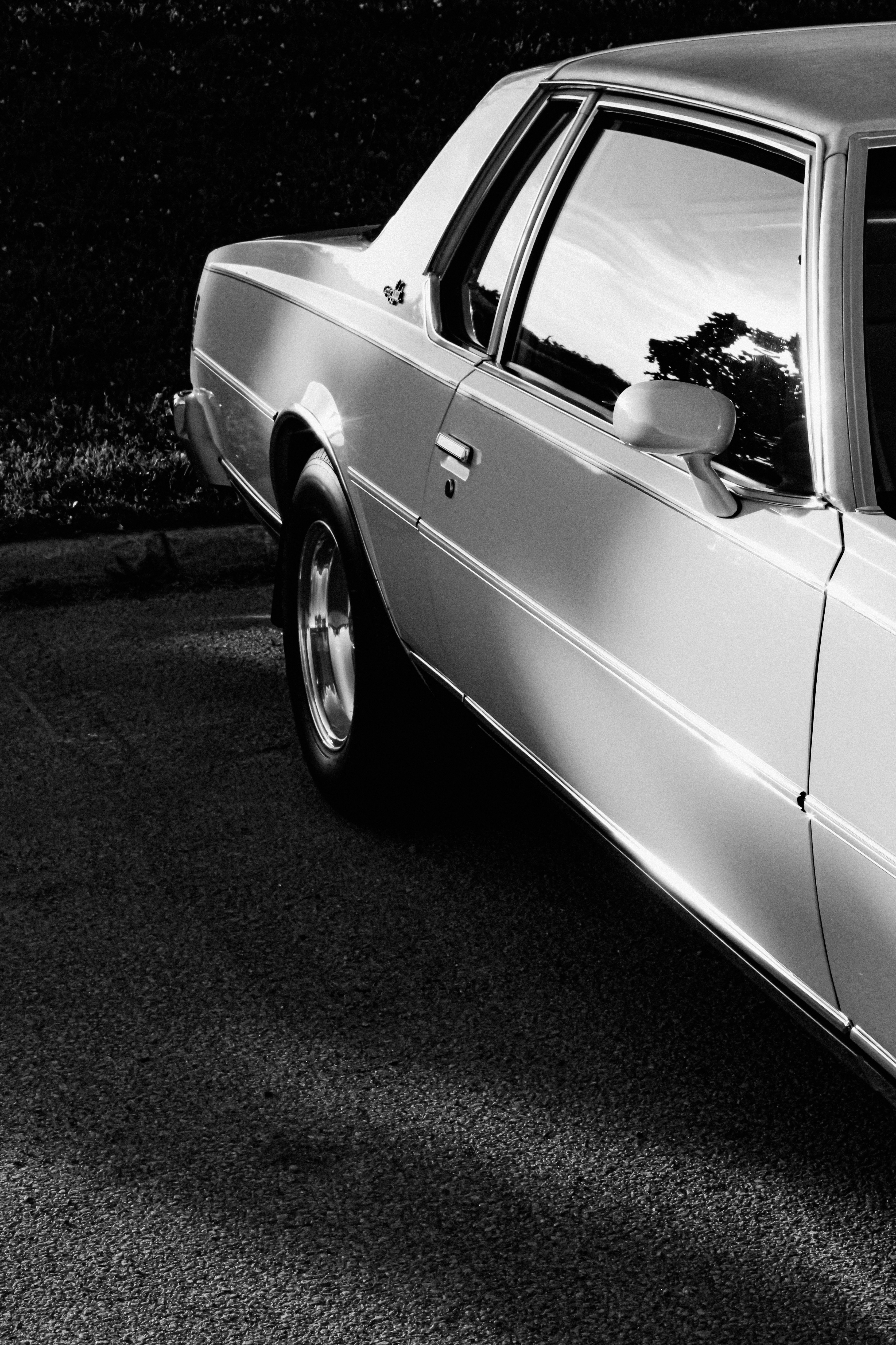 A black and white side view of a vintage car on asphalt